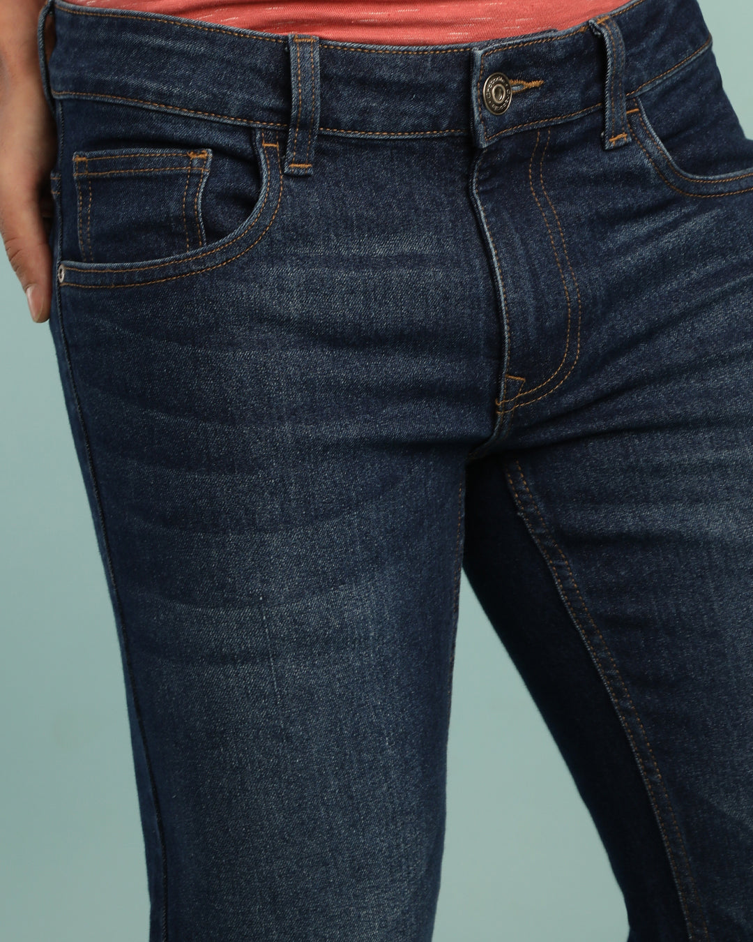 Man wearing a blue mid blue casual solid mid rise slim fit jean on a light gray background