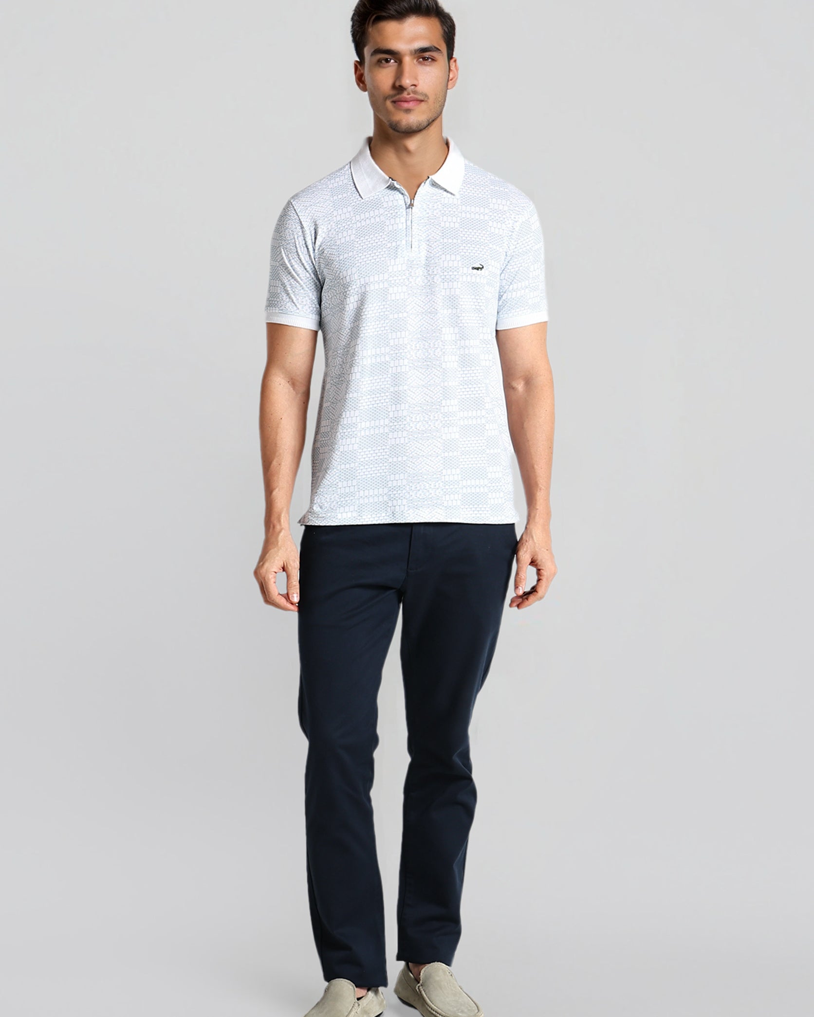 Man wearing a light gray polo shirt and dark pants on a white background