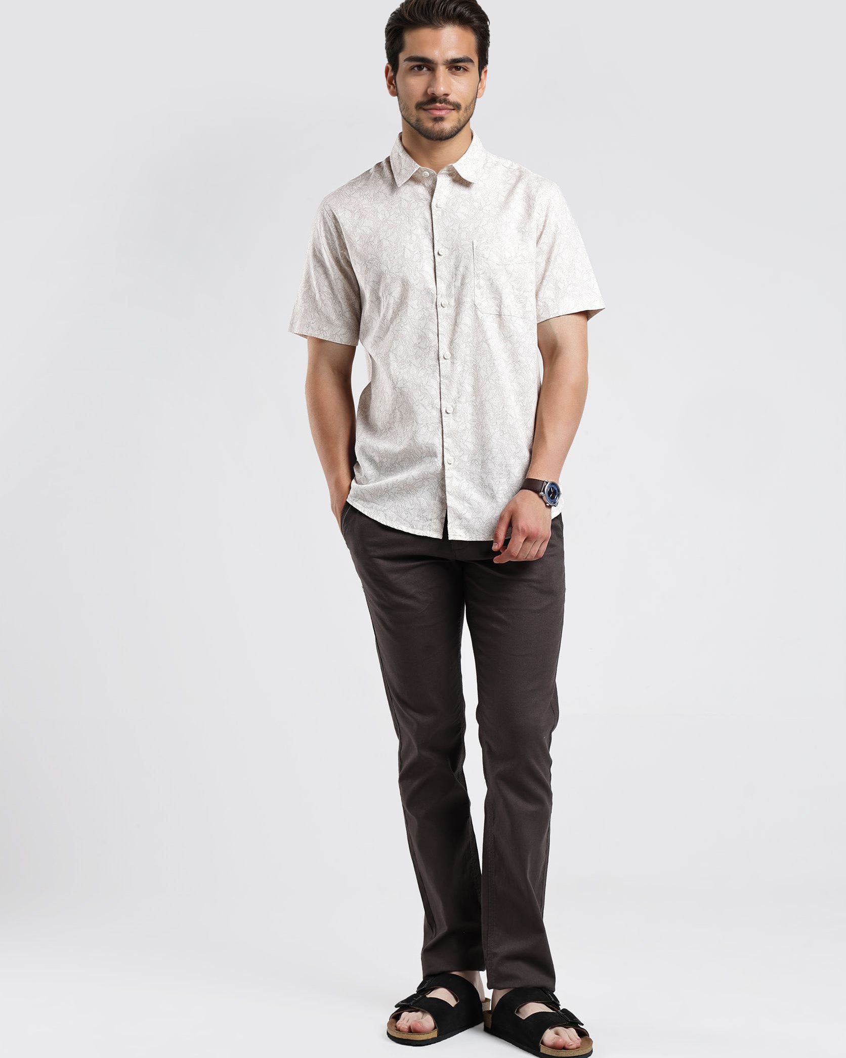 Man wearing a light-colored shirt and dark pants on a white background