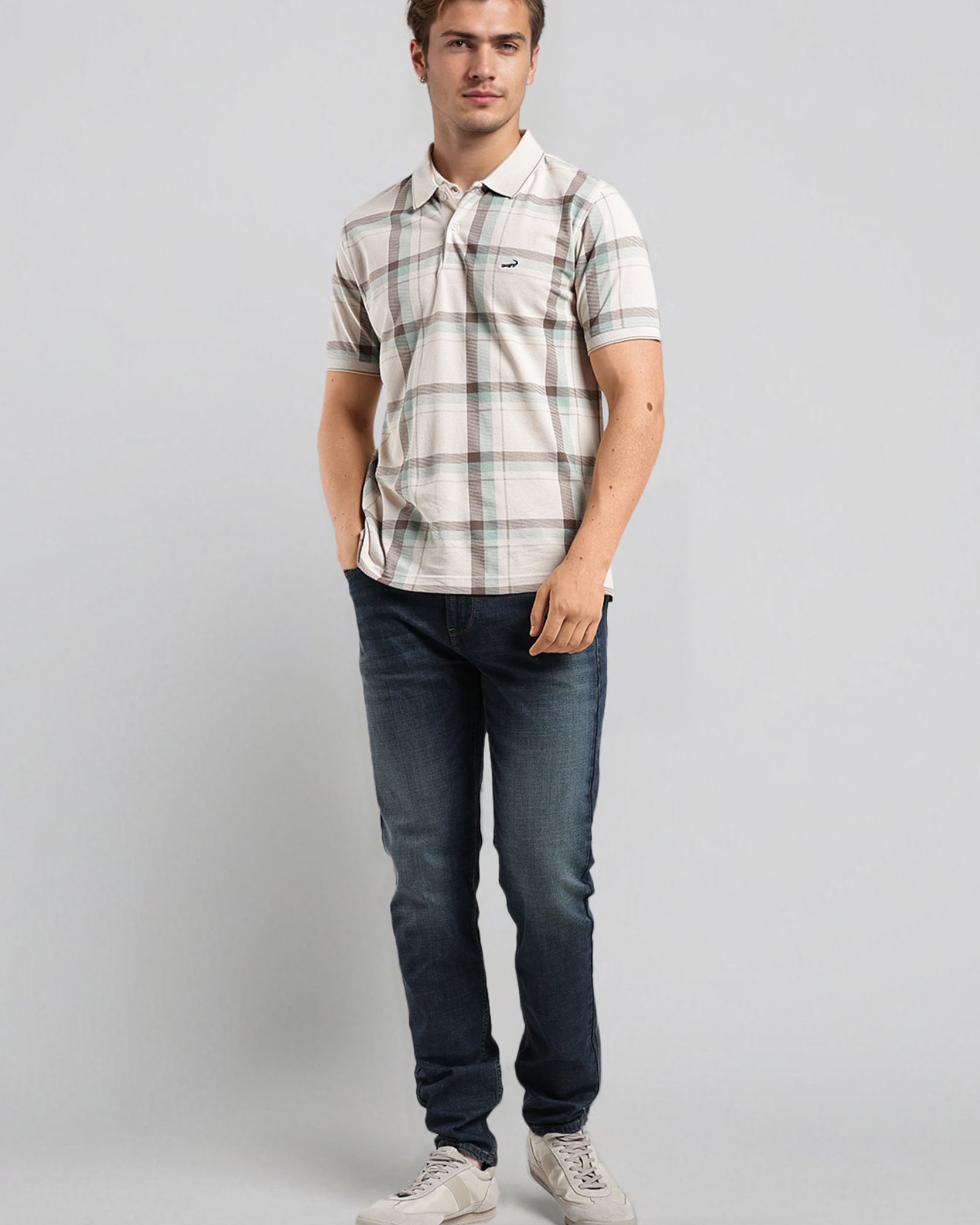 Man wearing a plaid shirt and jeans on a gray background