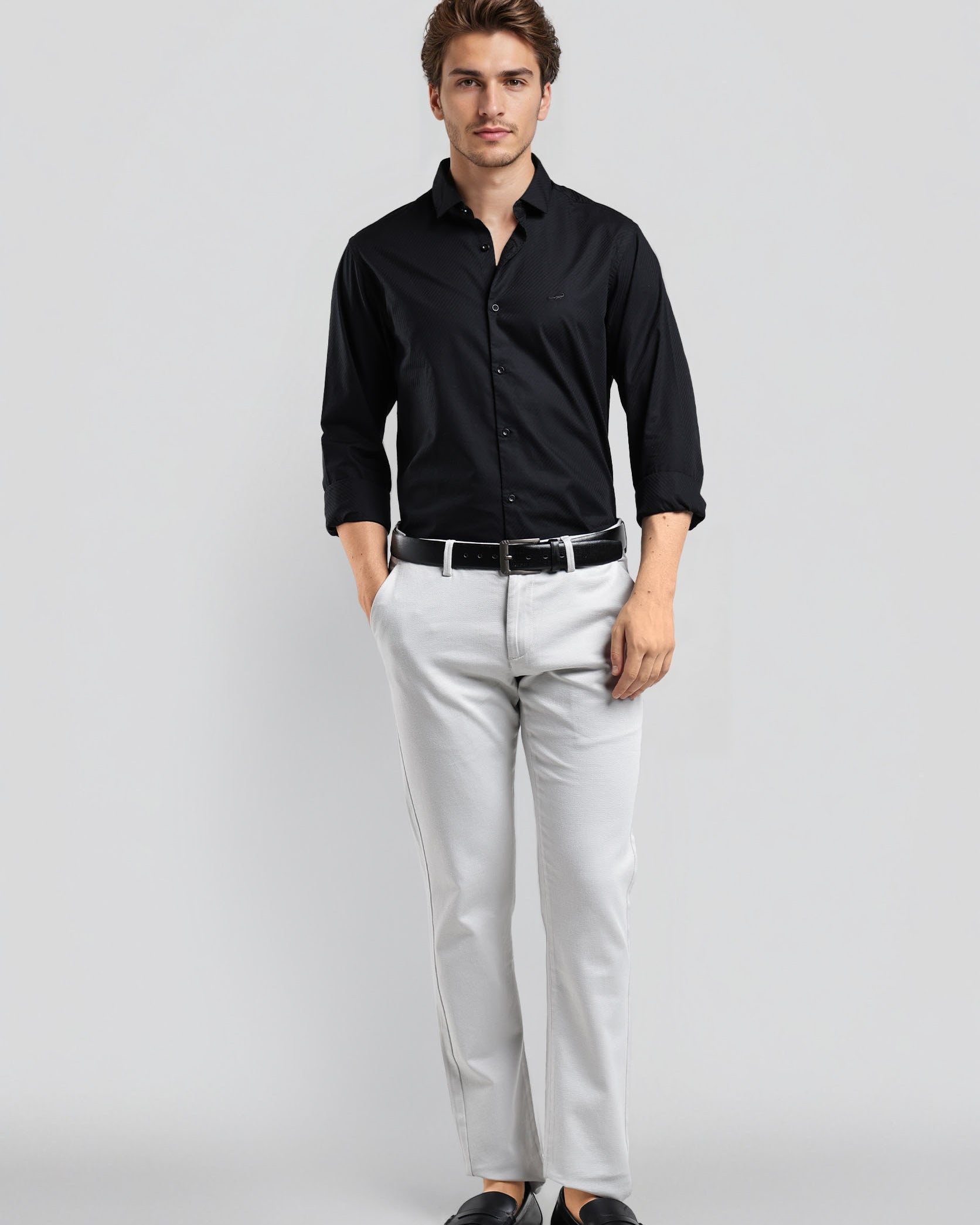 Man wearing a black shirt, white pants, and black shoes on a light gray background