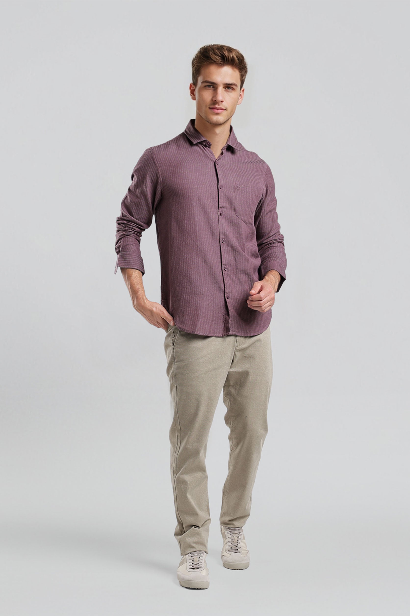 Man wearing a purple shirt and beige pants on a light gray background