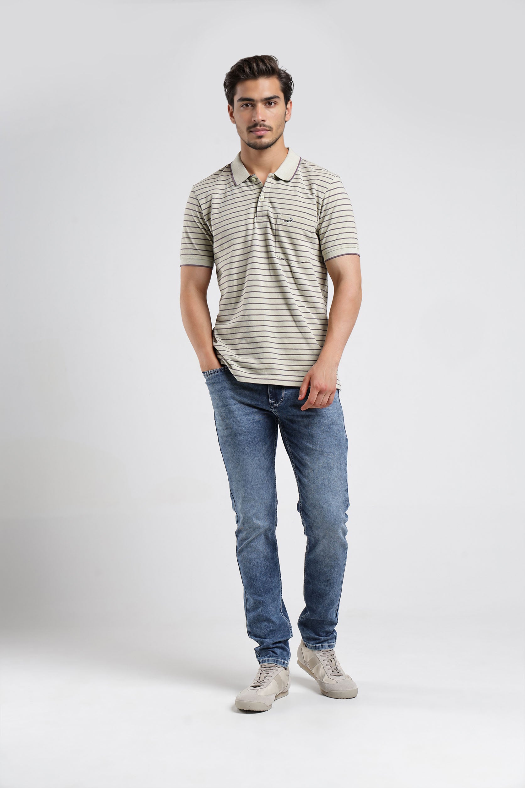 Man wearing a striped polo shirt and blue jeans on a white background