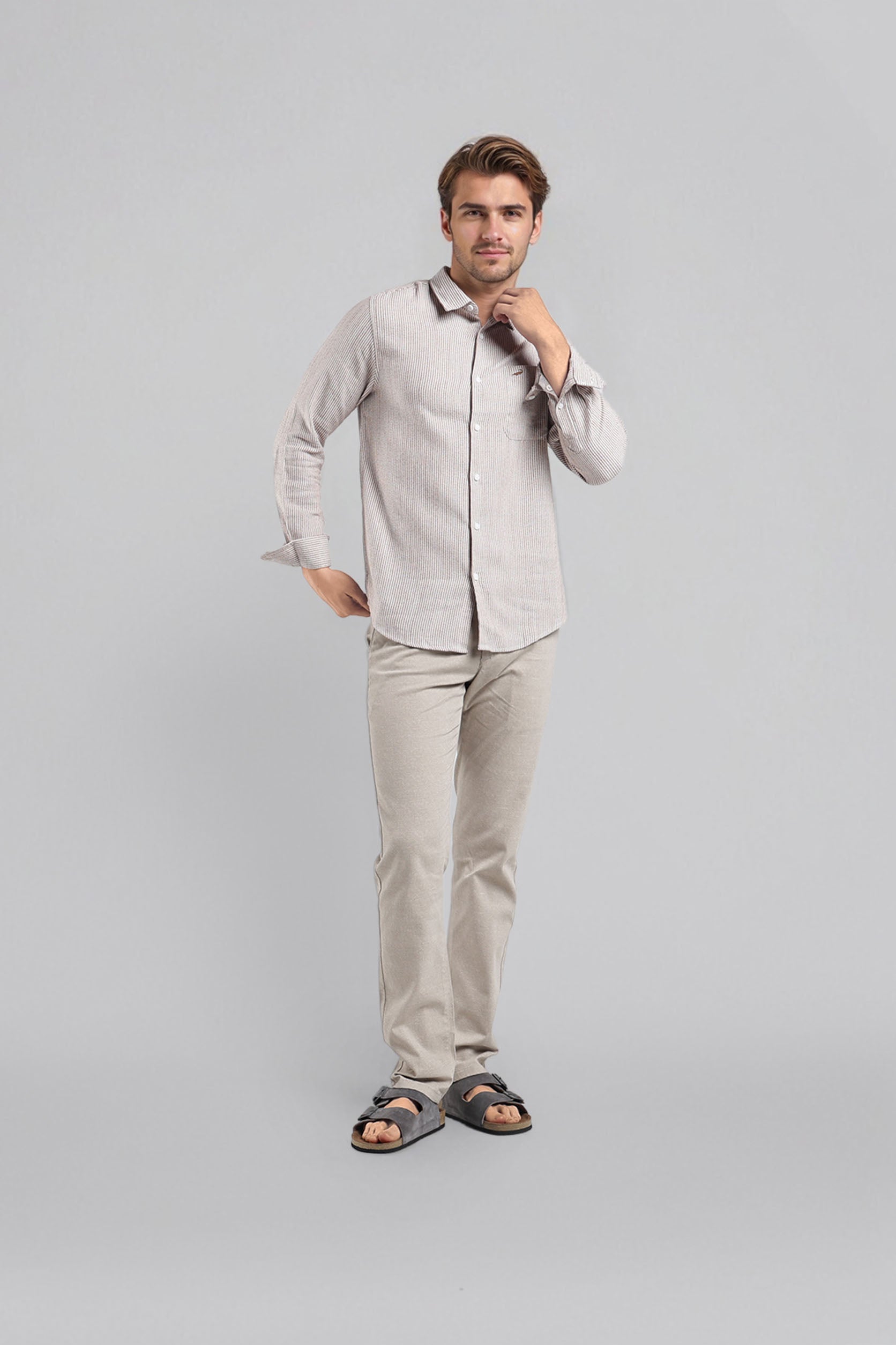 Man wearing a light gray shirt and beige pants against a gray background