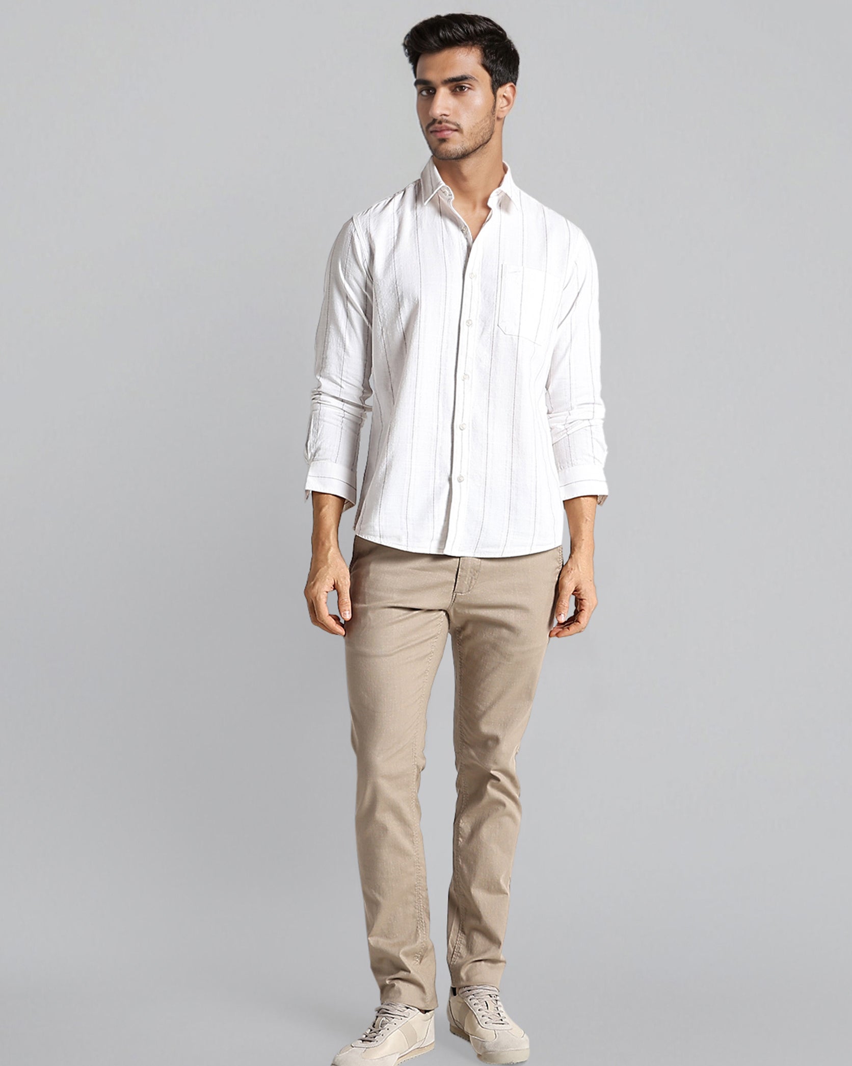 Man wearing a white shirt and beige pants on a gray background
