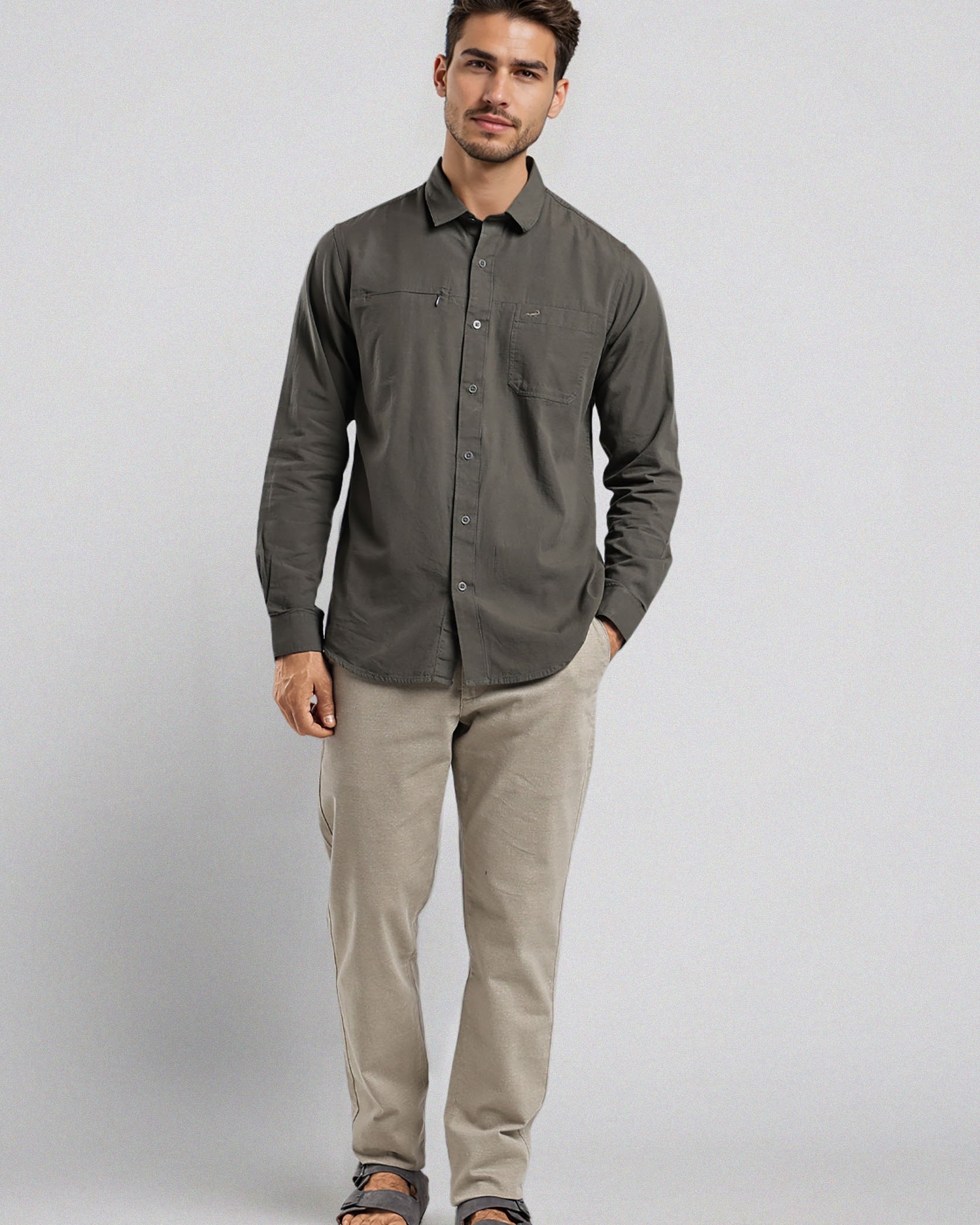 Man wearing a dark gray button-up shirt and beige pants on a light gray background