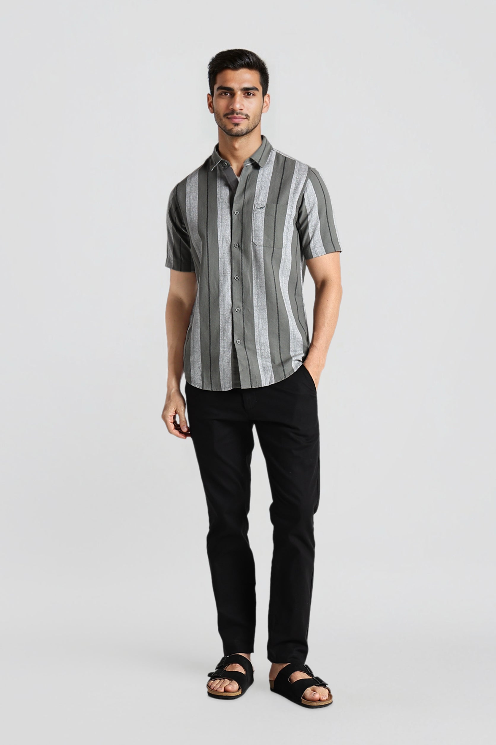 Man wearing a gray striped shirt and black pants on a light gray background