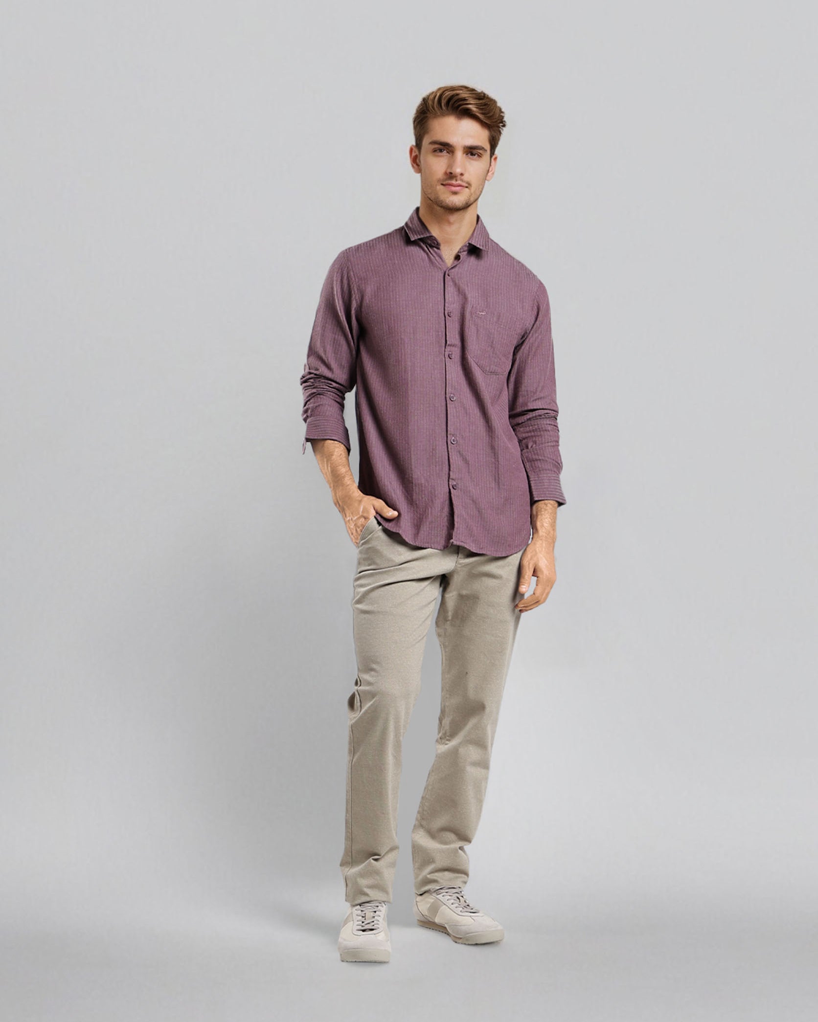 Man wearing a purple shirt and beige pants on a gray background