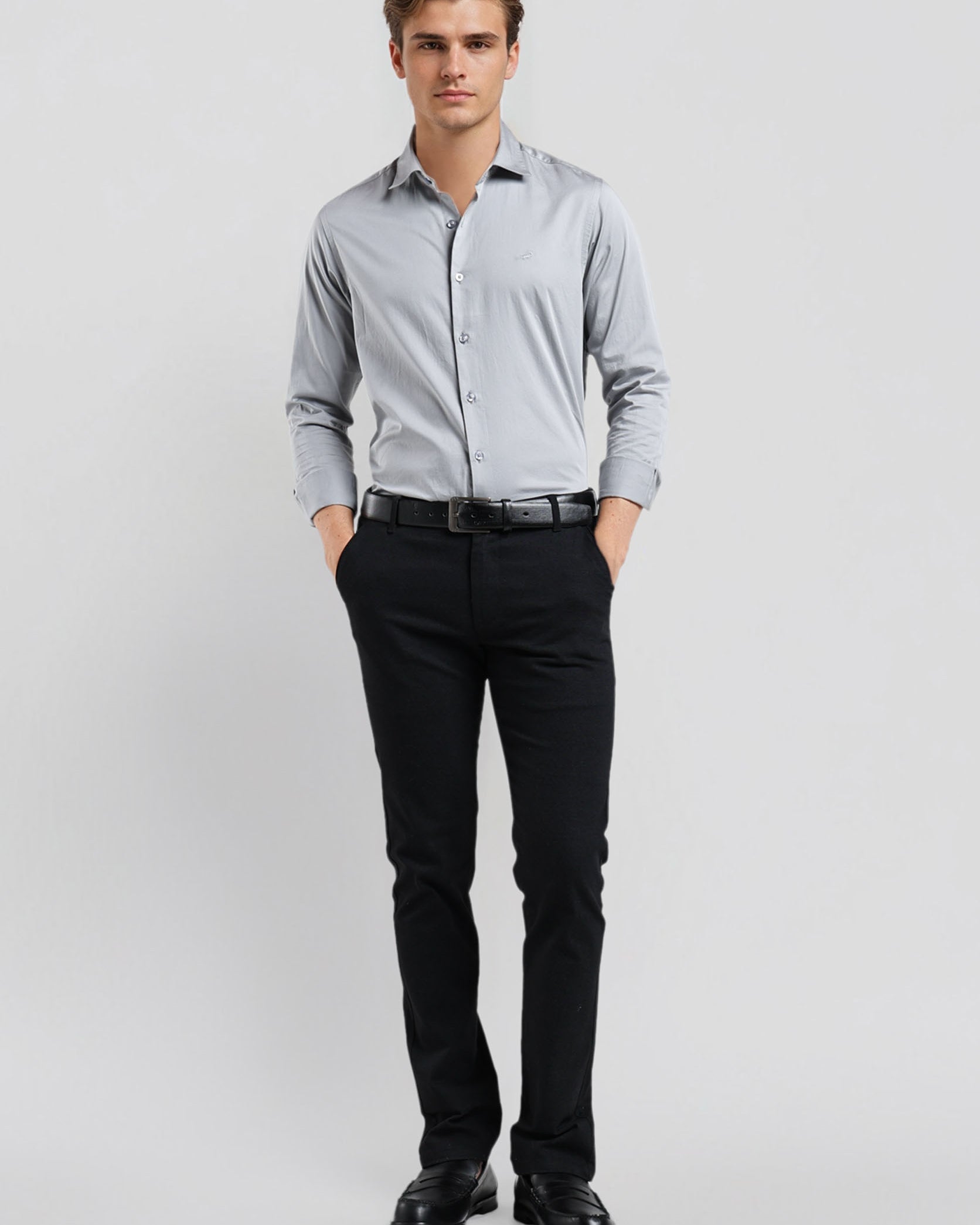 Man wearing a light gray dress shirt and black pants on a white background