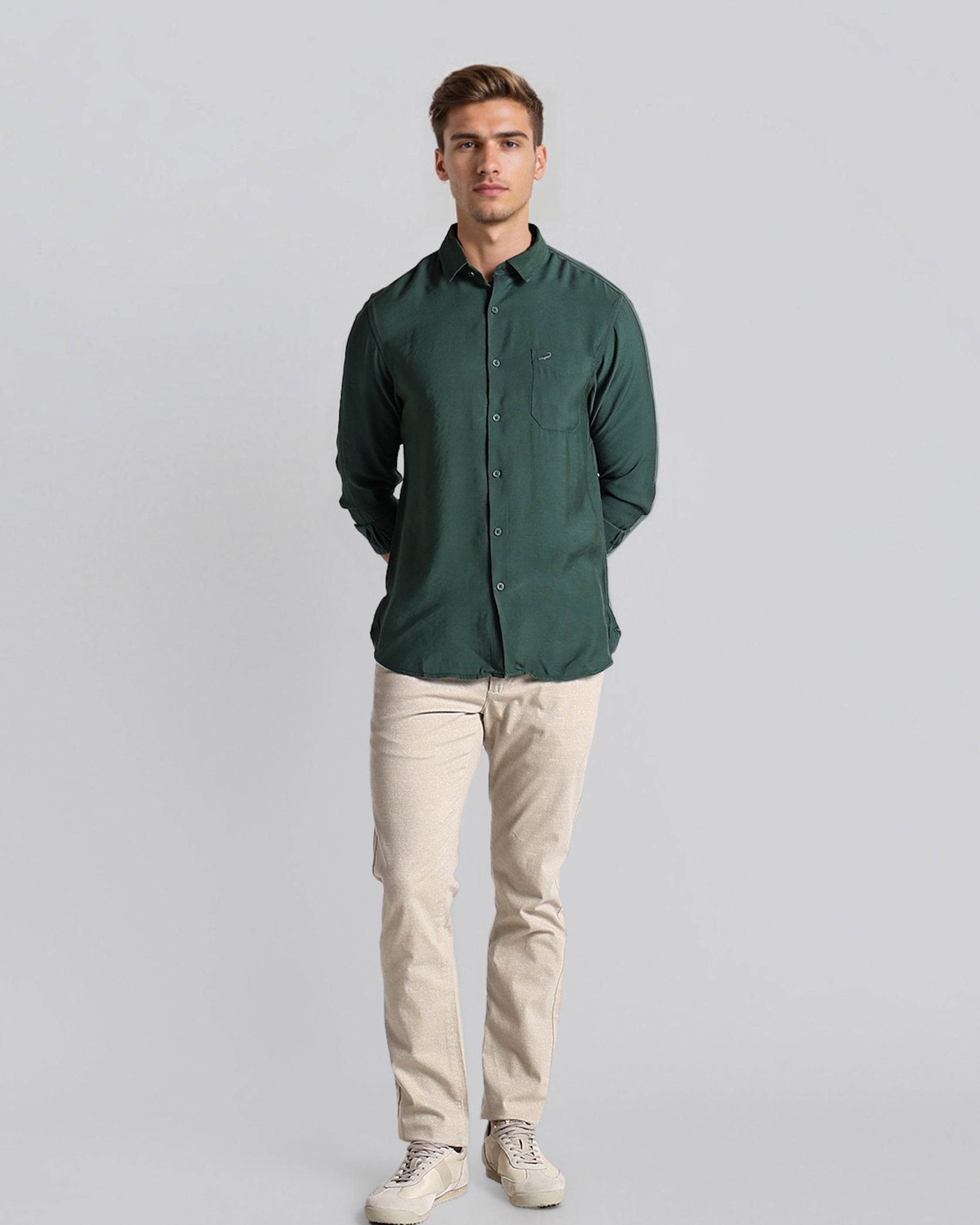 Man wearing a green shirt and beige pants on a gray background