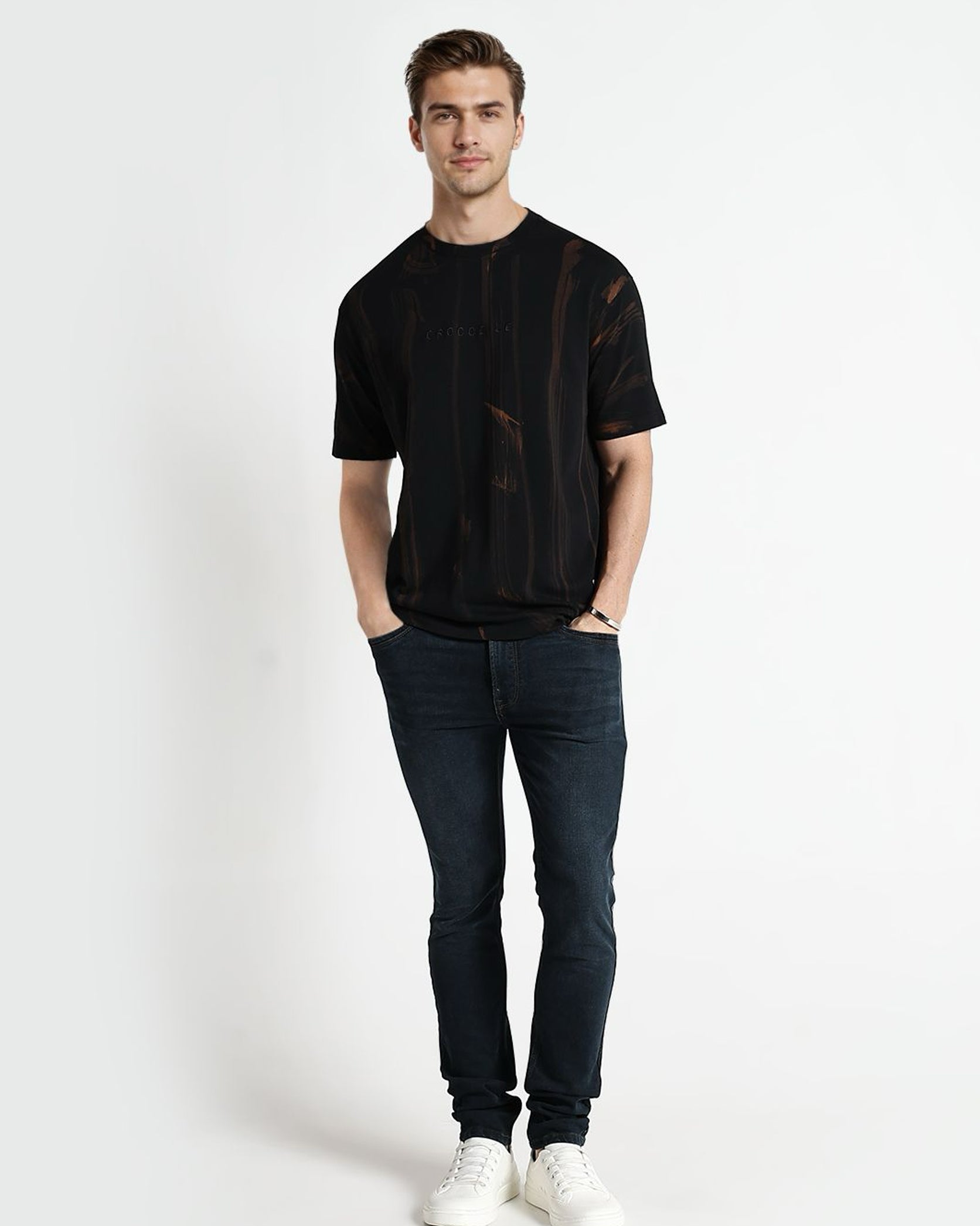 Man wearing a black t-shirt and dark jeans on a white background