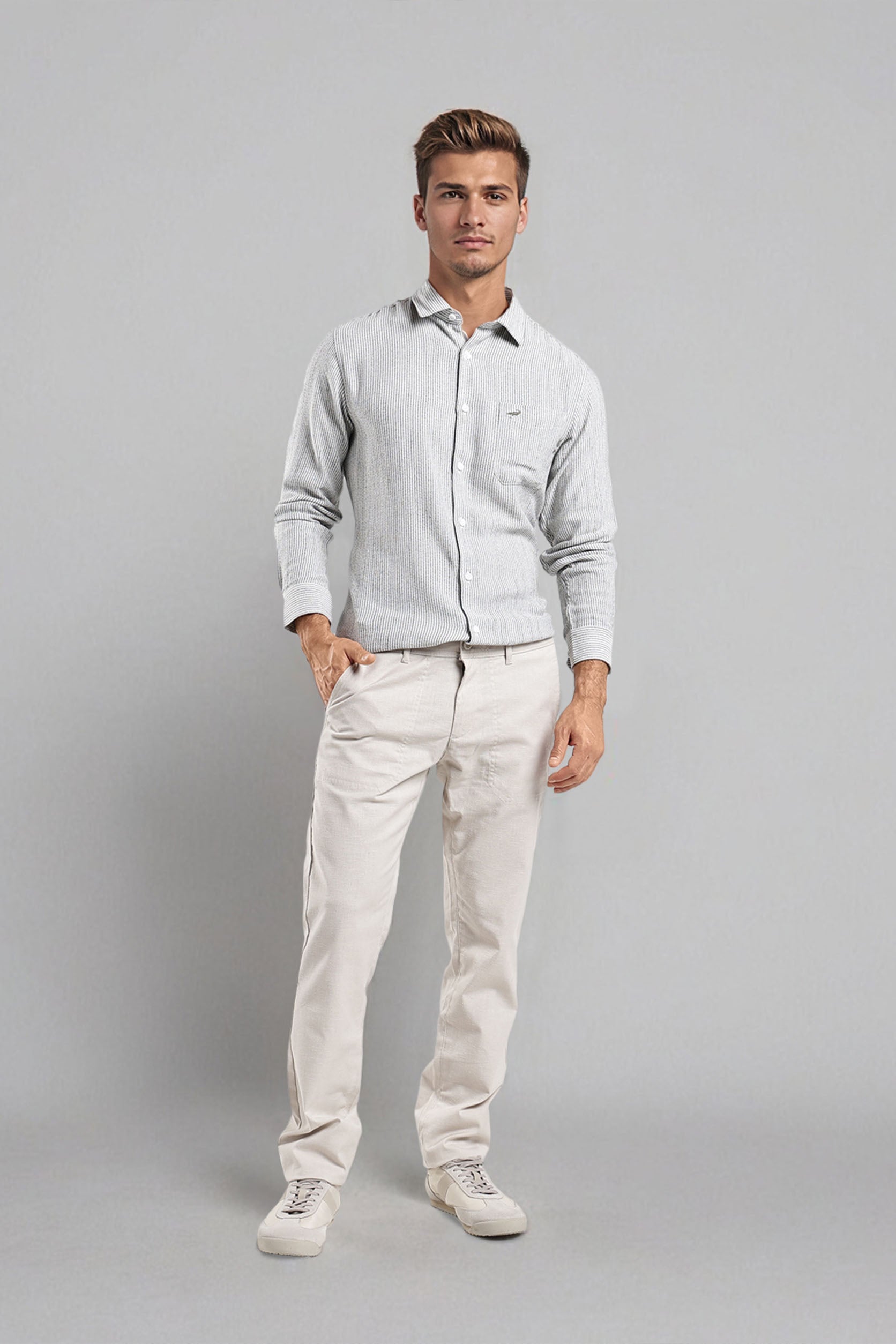 Man wearing a light gray shirt and beige pants on a gray background