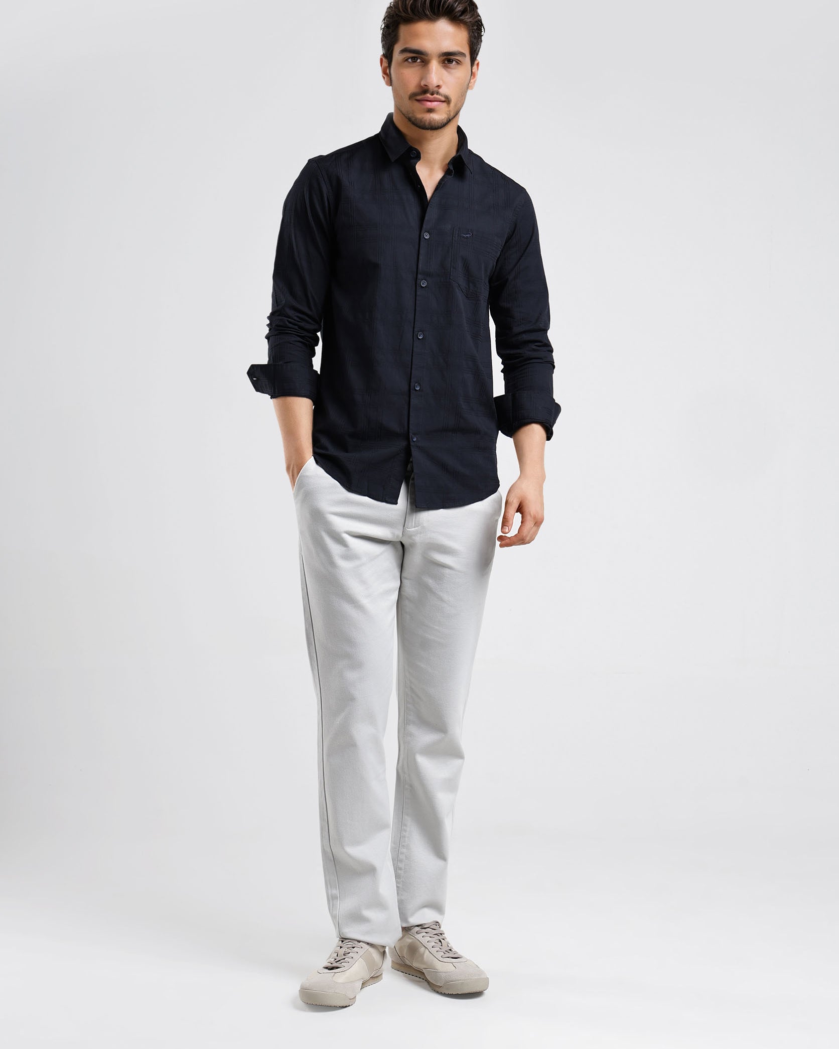 Man wearing a black shirt and light gray pants on a white background