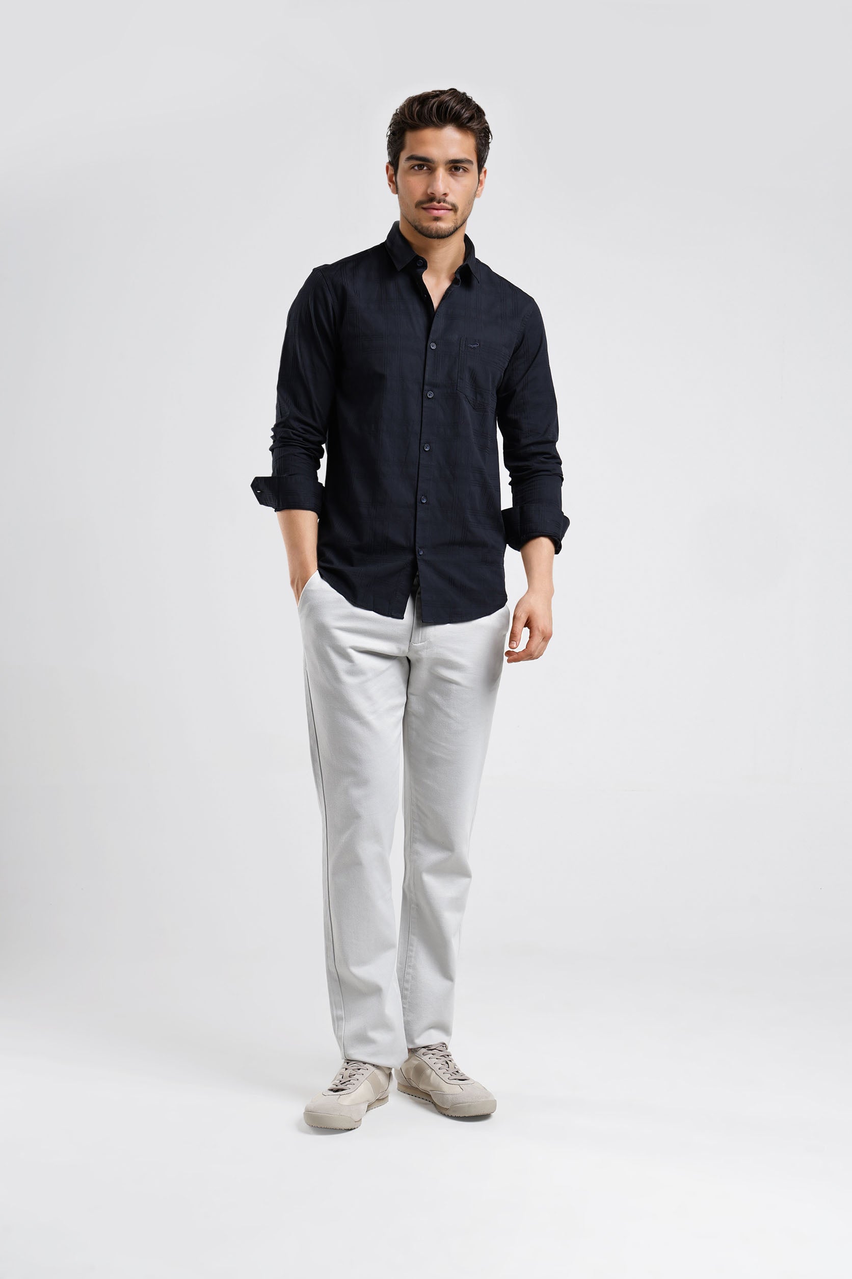 Man wearing a black shirt and light gray pants on a white background