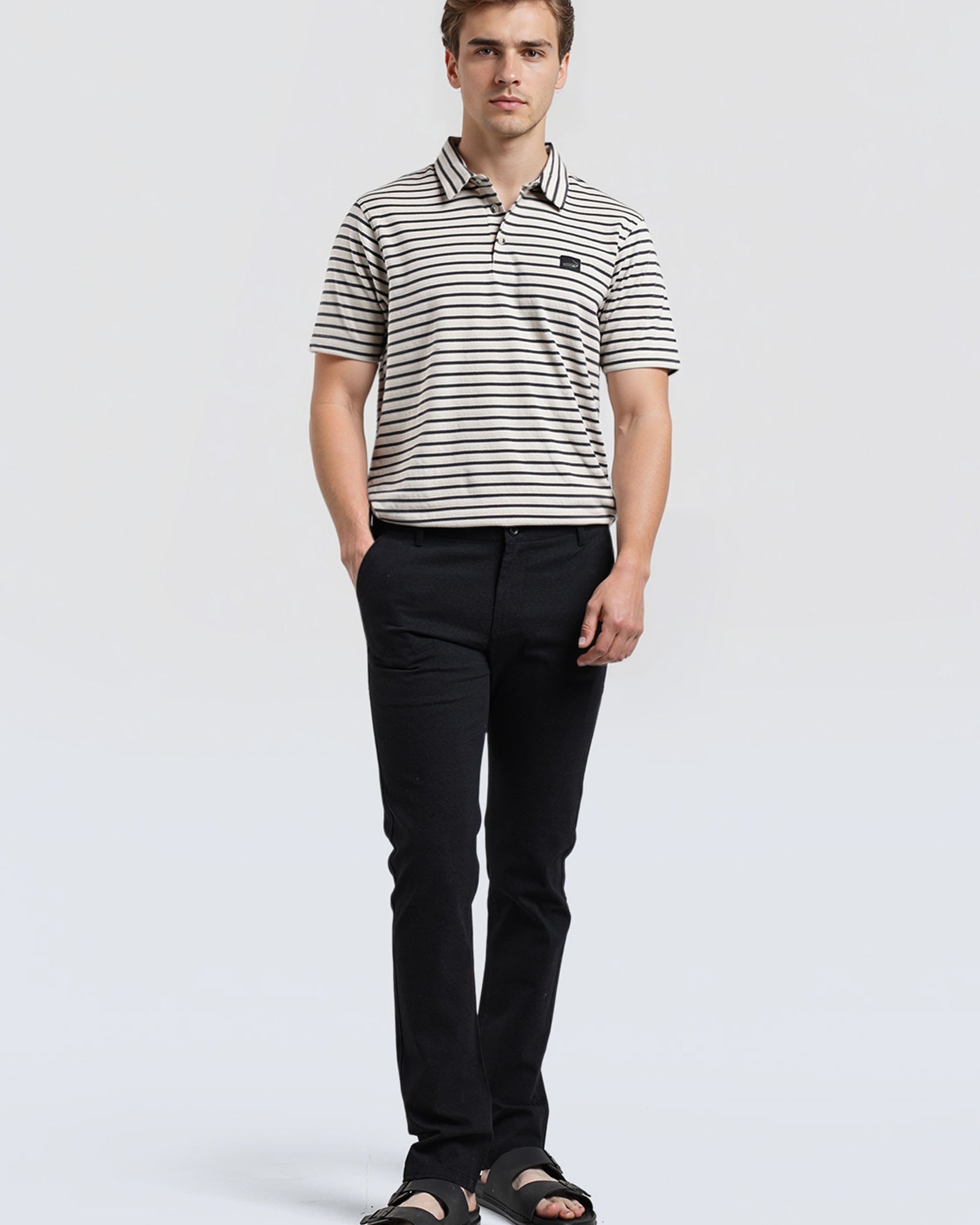 Man wearing a striped polo shirt and black pants on a white background