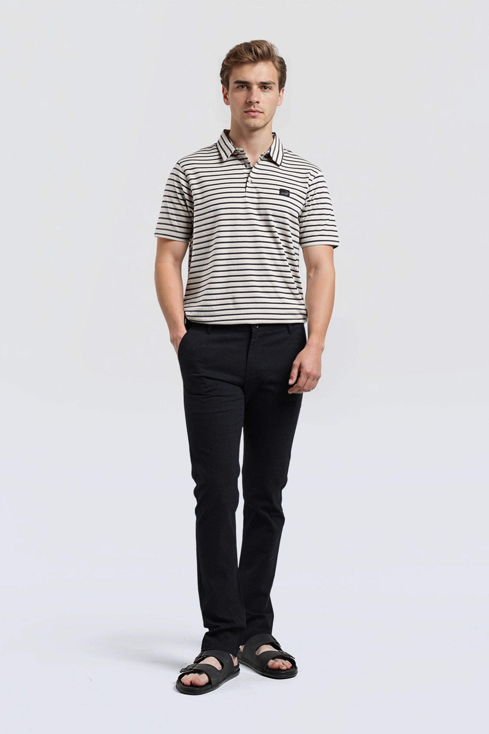 Man wearing a striped polo shirt and black pants on a white background
