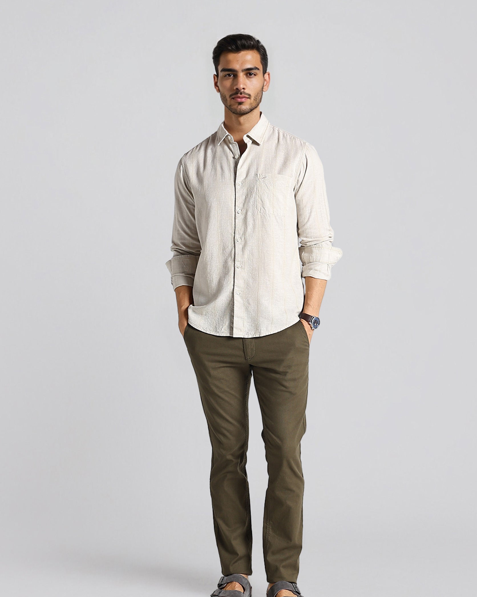 Man wearing a beige shirt and green pants on a gray background