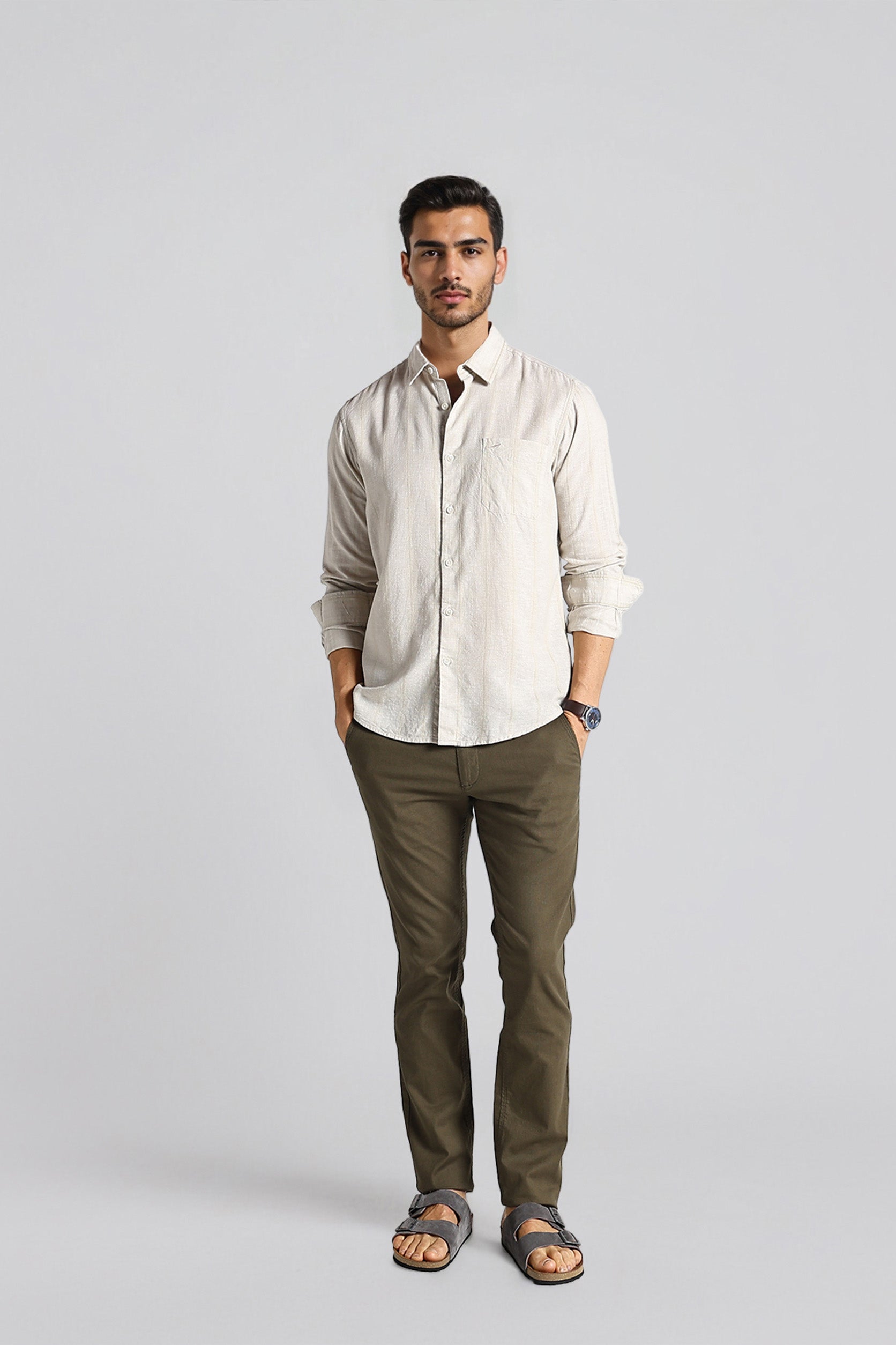 Man wearing a beige shirt and green pants on a gray background