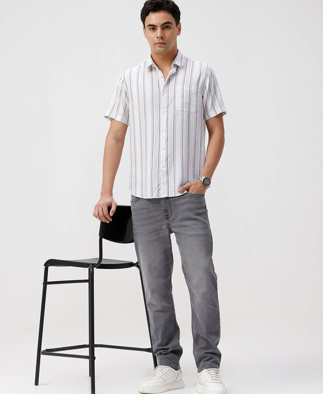 Man wearing a white white and green stripes comfort fit casuals shirts on a light gray background