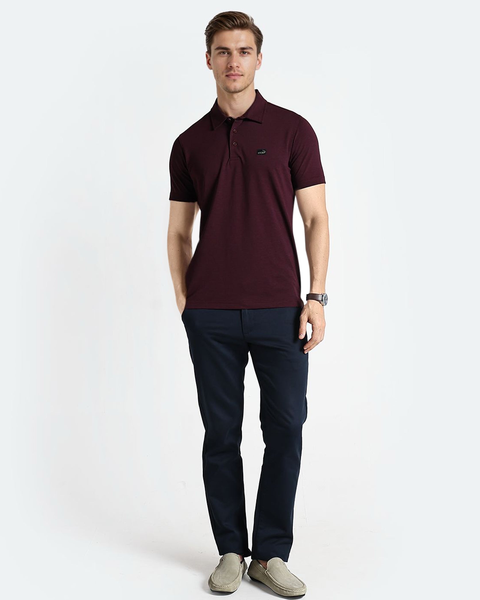 Man wearing a maroon polo shirt and dark pants on a white background
