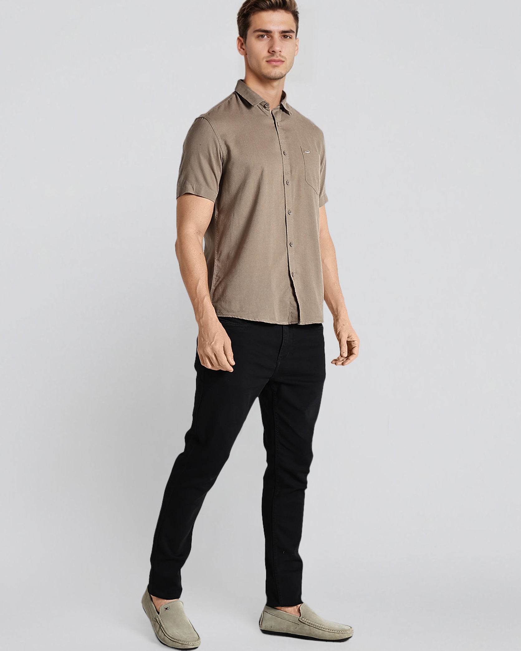 Man wearing a beige short-sleeve shirt and black pants on a white background