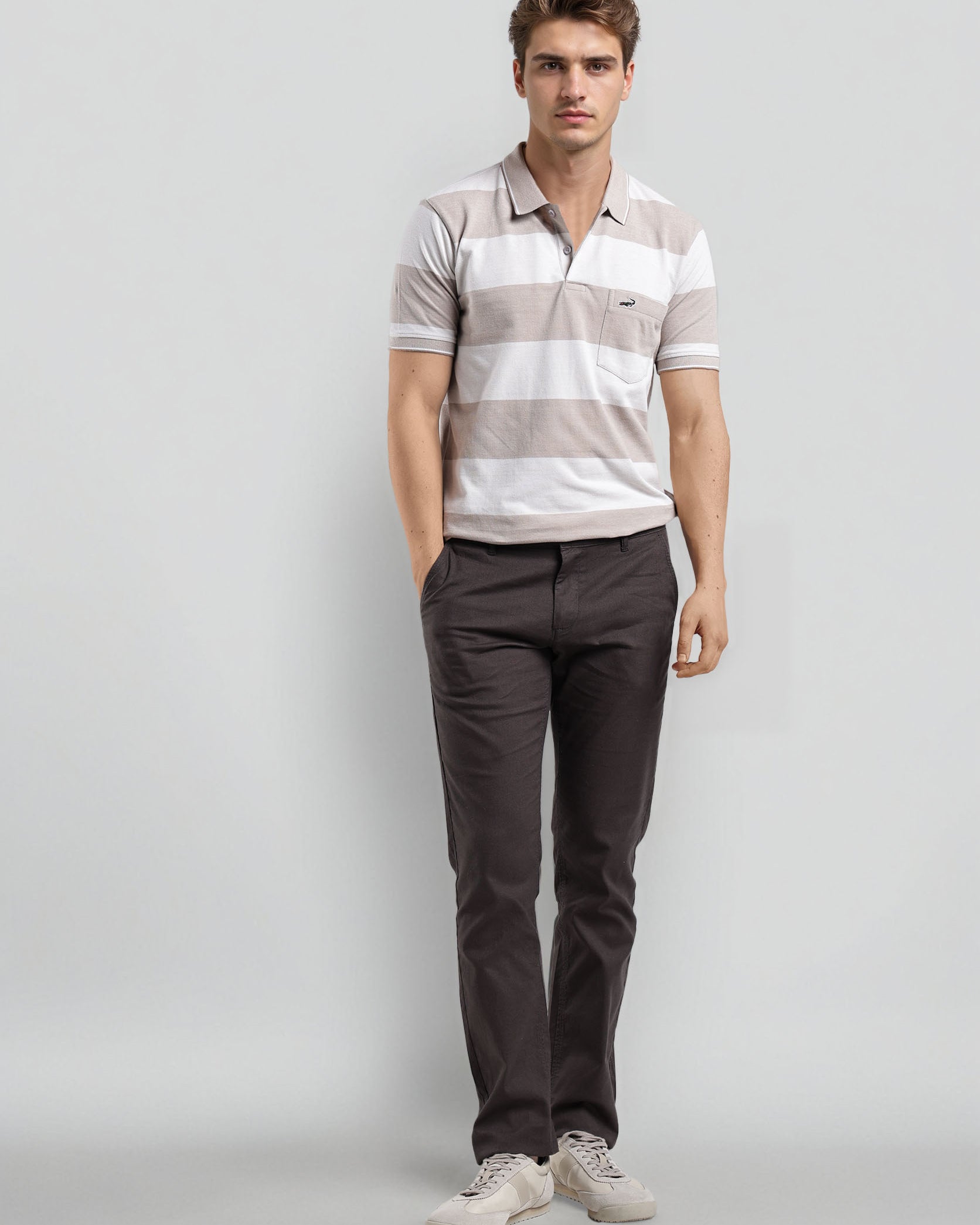 Man wearing a striped polo shirt and dark pants on a gray background