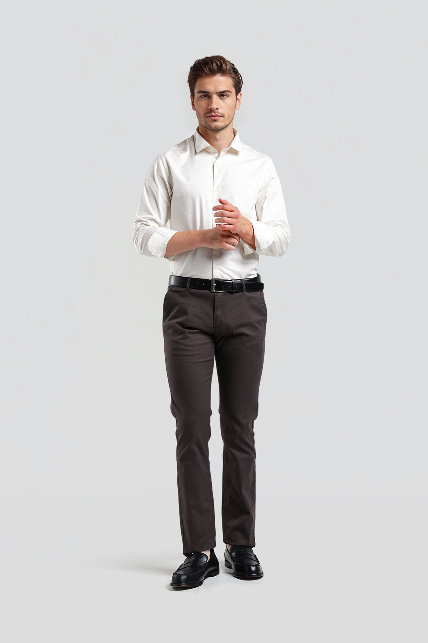 Man wearing a white shirt and dark pants on a light gray background