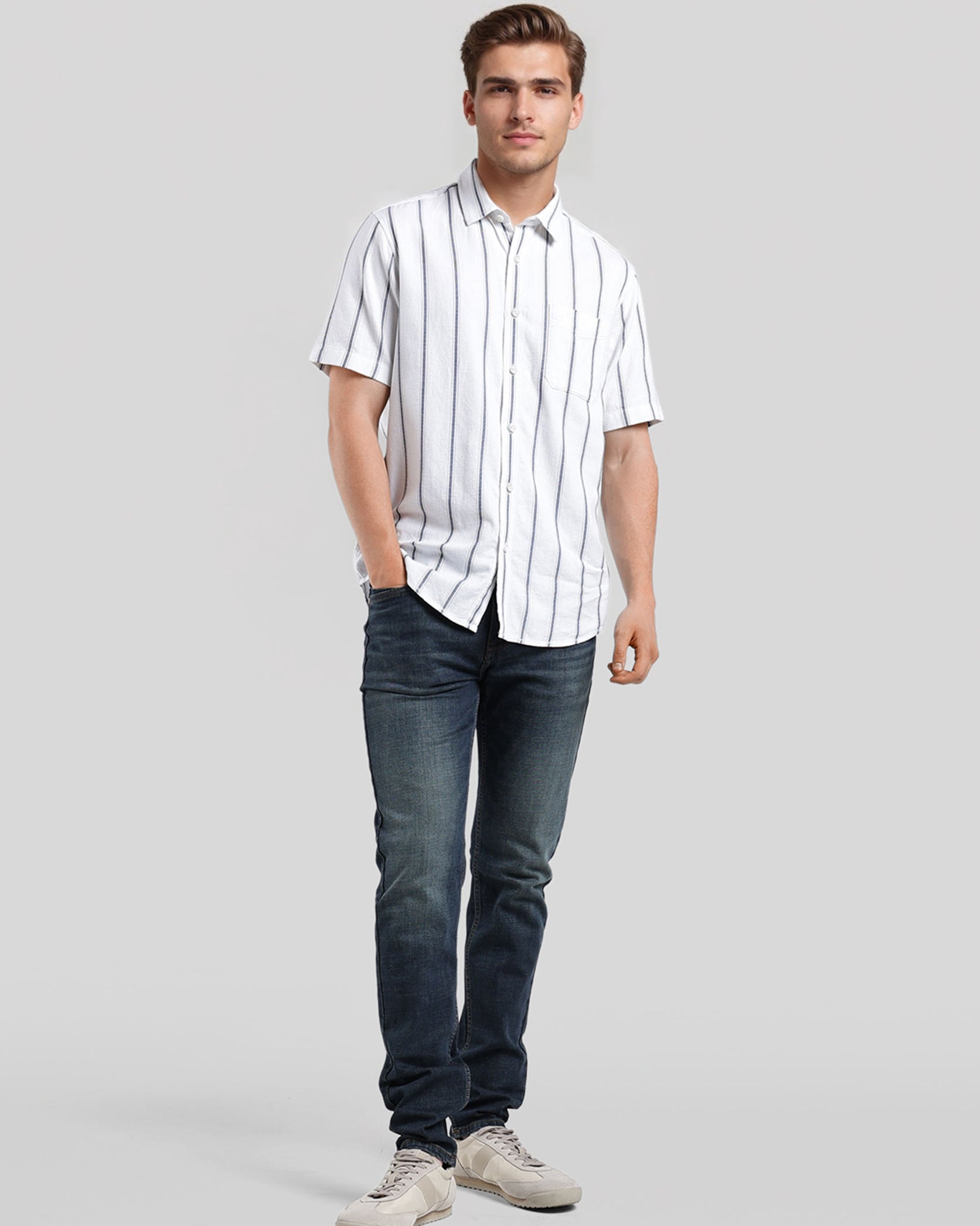 Man wearing a white striped shirt and blue jeans on a gray background