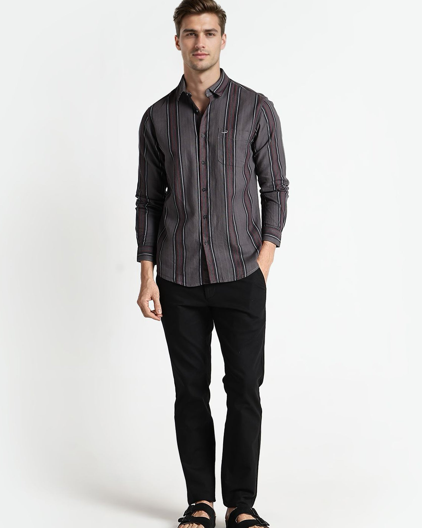 Man wearing a striped shirt and black pants on a white background