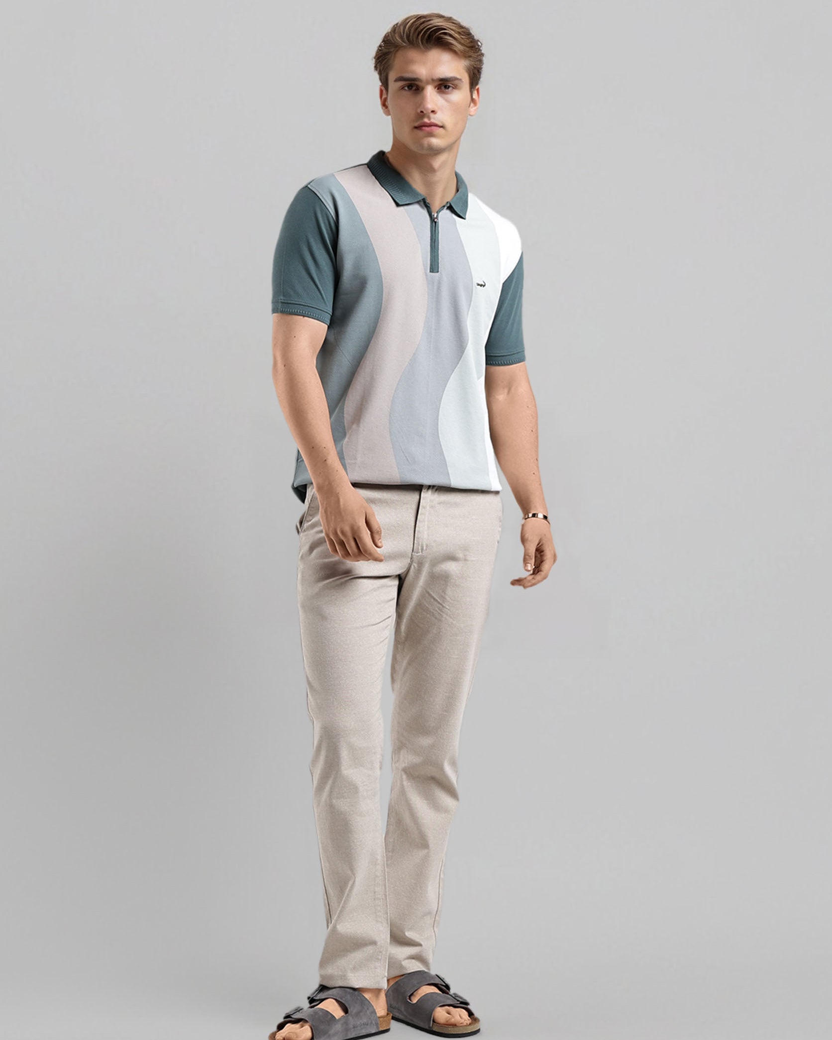 Man wearing a color-blocked polo shirt and beige pants on a gray background