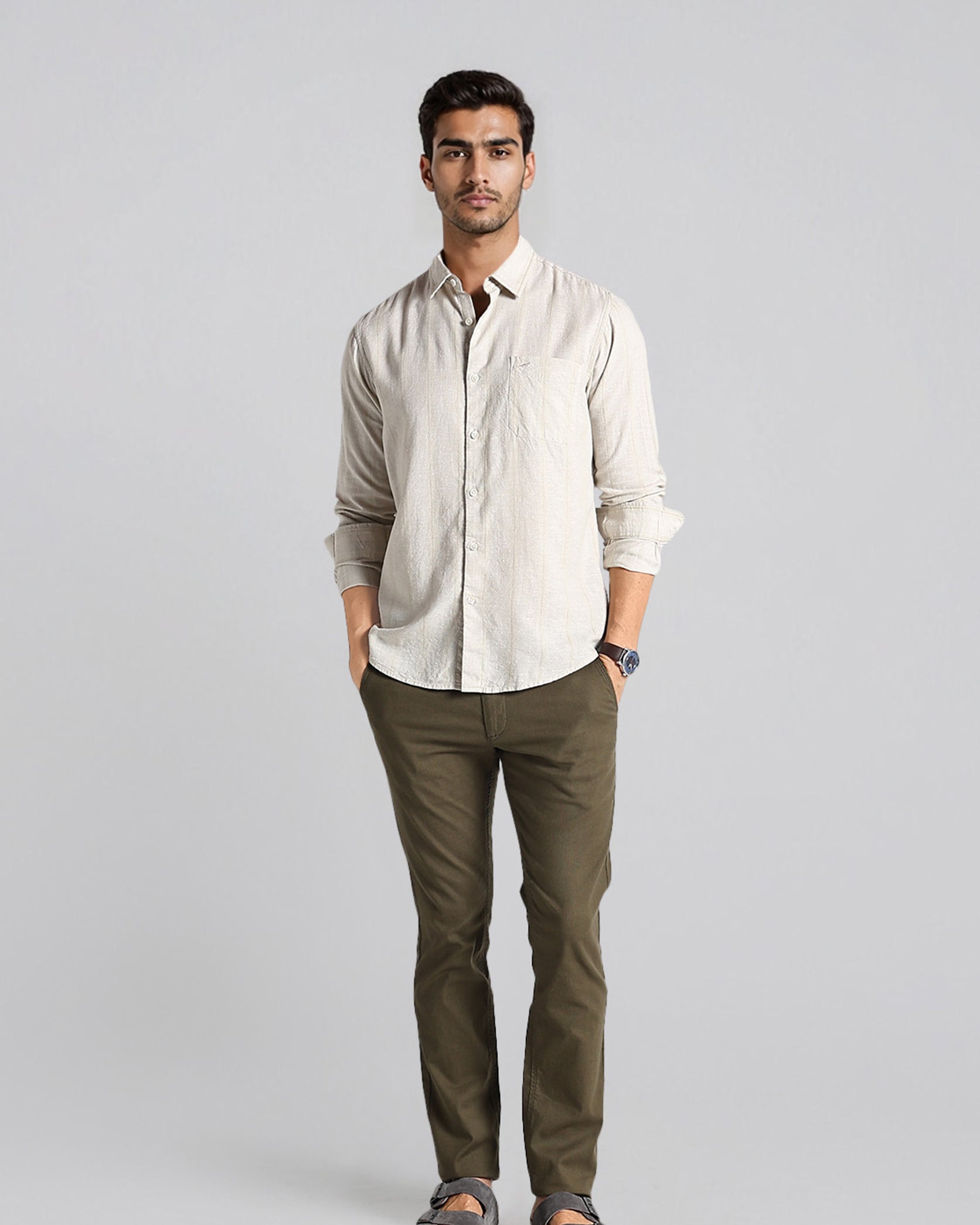 Man wearing a beige shirt and green pants on a gray background