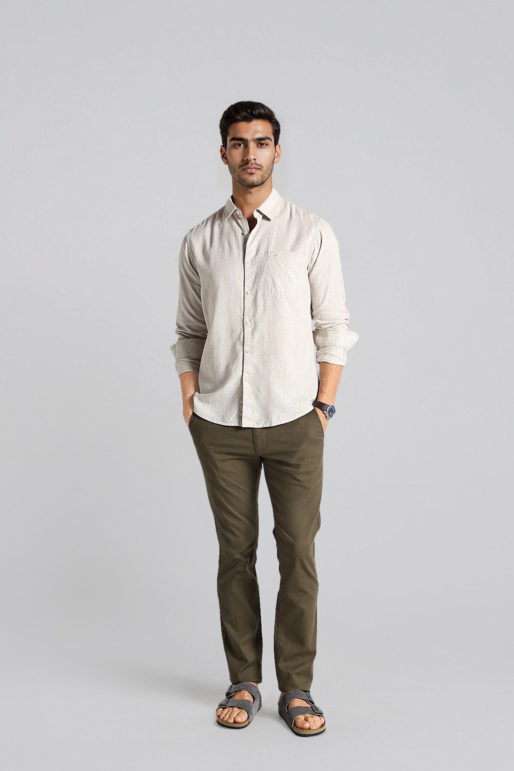 Man wearing a beige shirt and green pants on a gray background