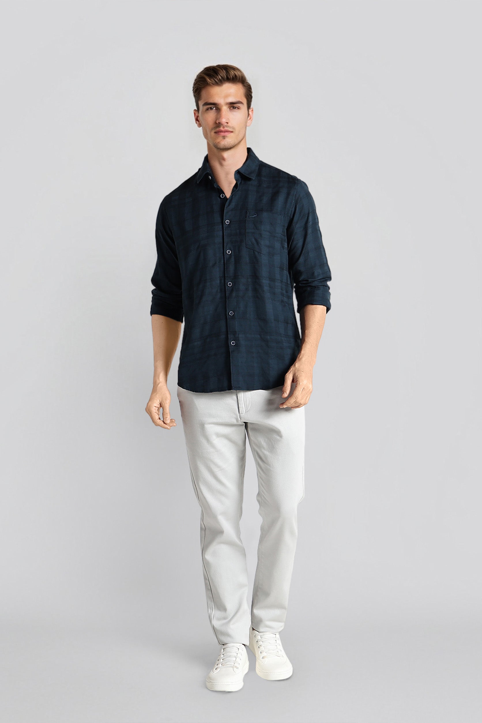 Man wearing a dark blue shirt and light gray pants on a gray background