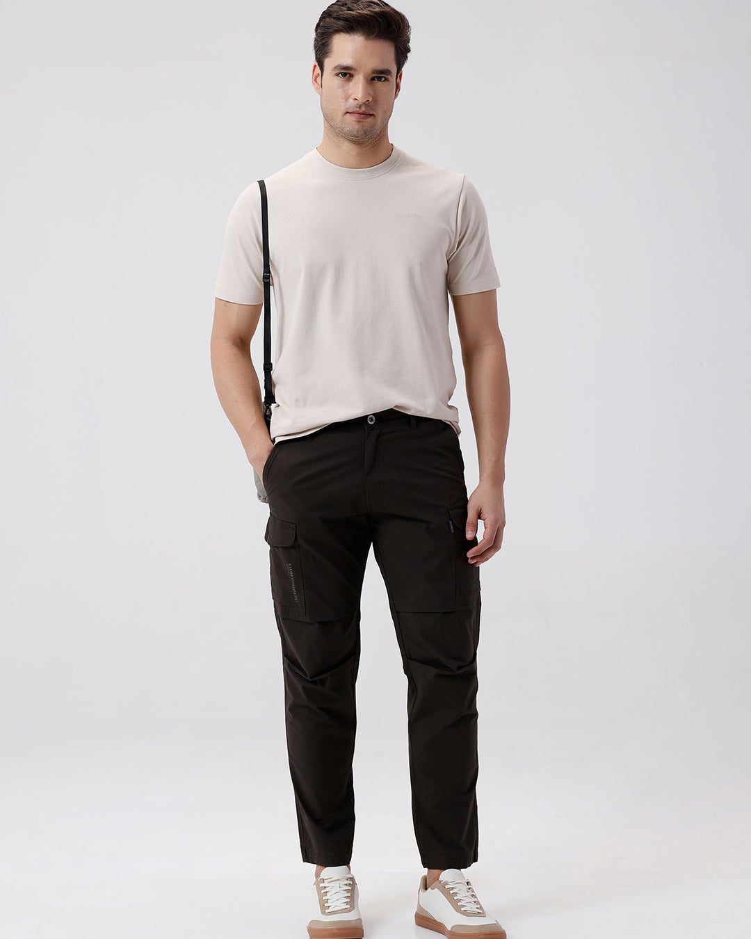 Man wearing a grey utility trekflex cargo pant in dark grey on a light gray background