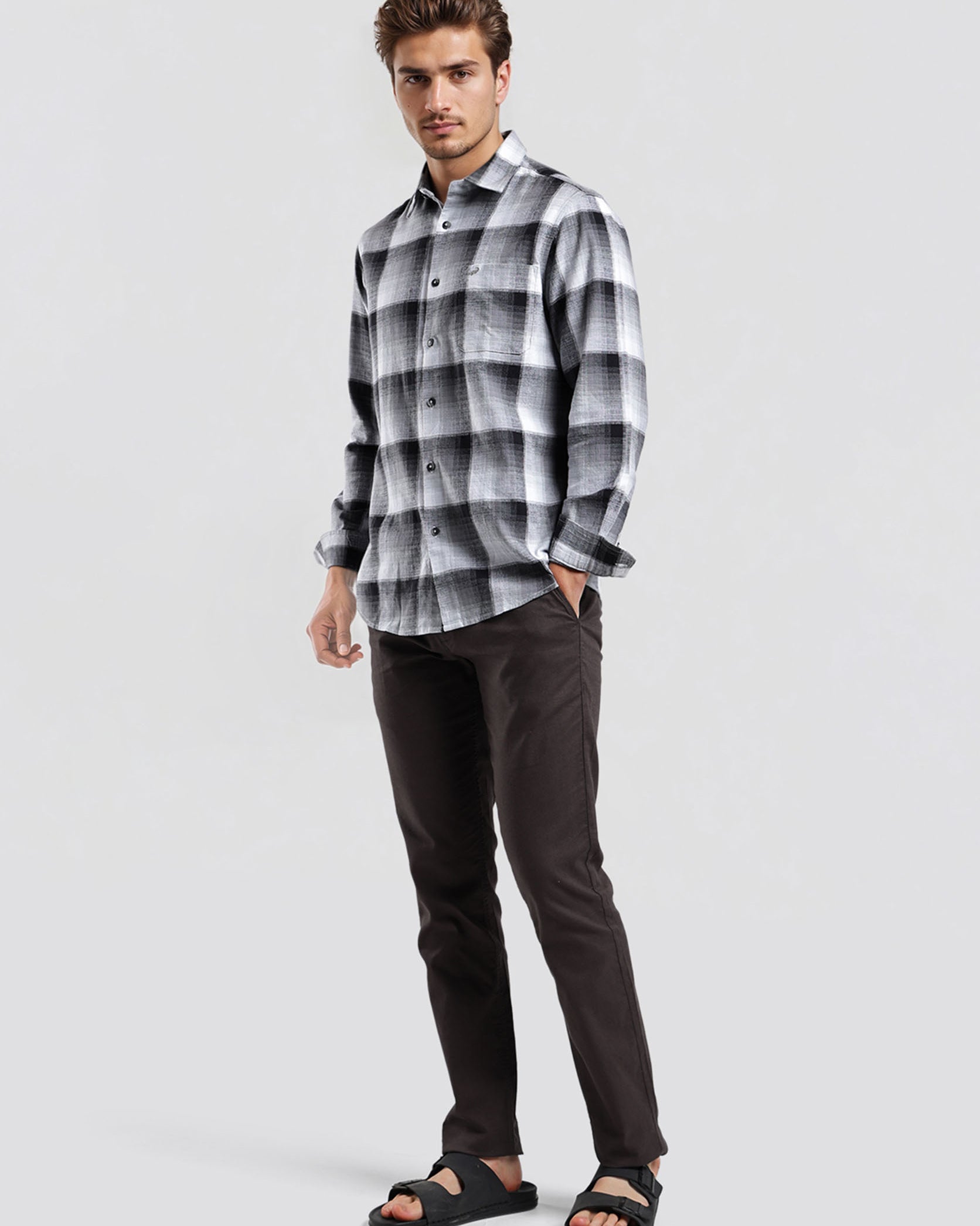 Man wearing a plaid shirt and dark pants on a white background