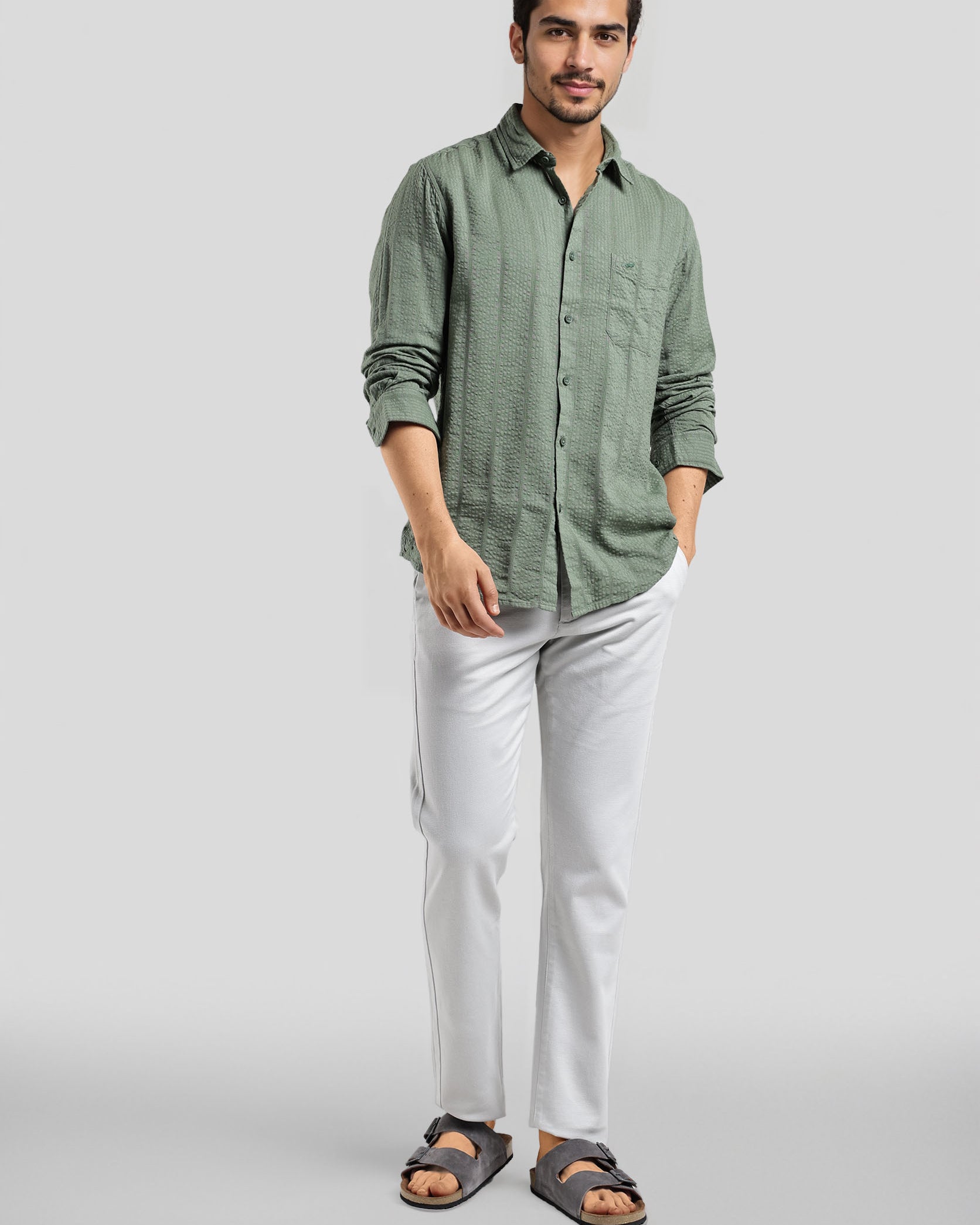 Man wearing a green shirt and white pants on a gray background