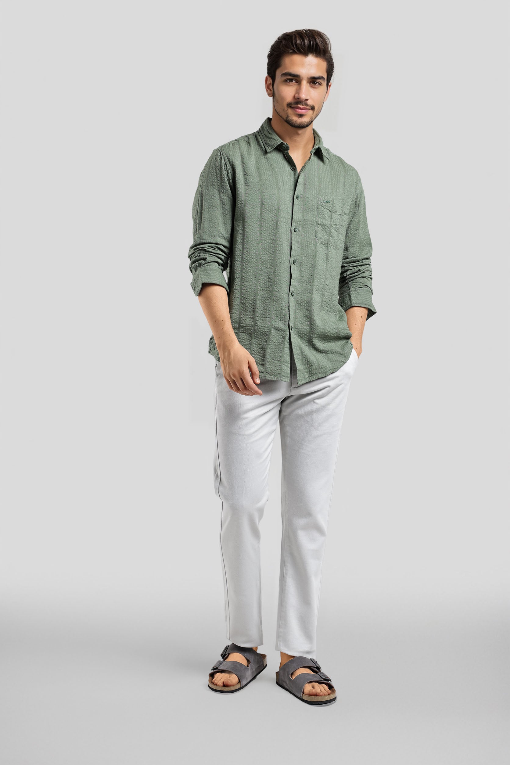 Man wearing a green shirt and white pants on a gray background