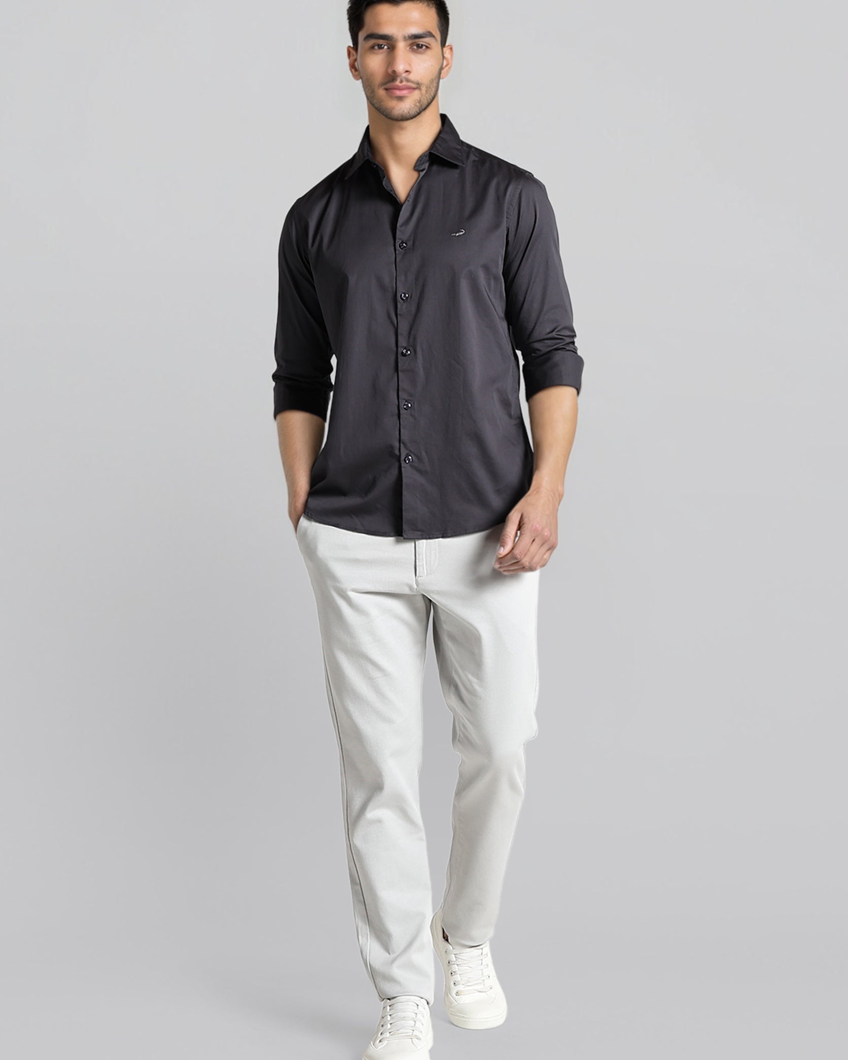 Man wearing a black shirt and white pants on a gray background