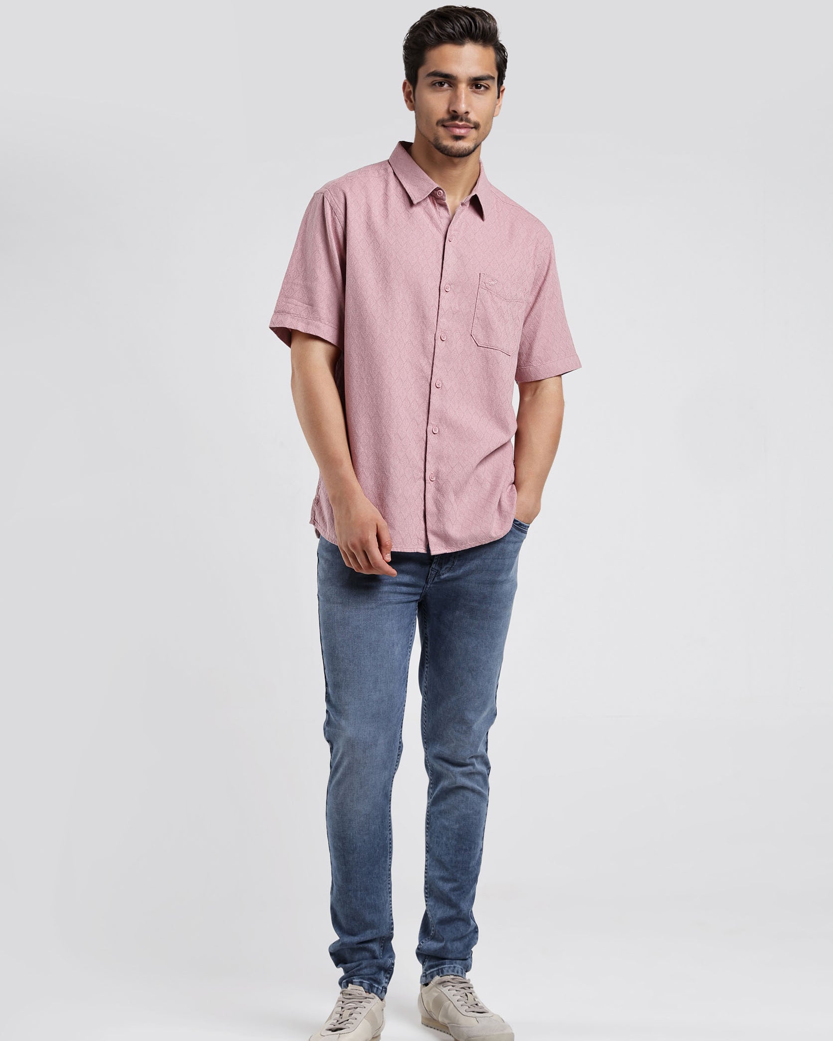 Man wearing a pink shirt and blue jeans on a white background