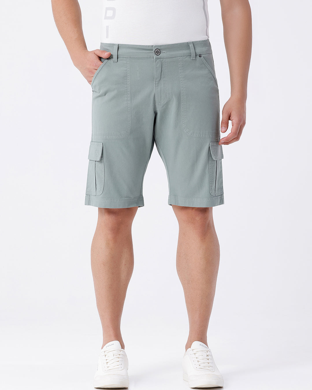 Man wearing a olive garment dyed cargo shorts in olive on a light gray background