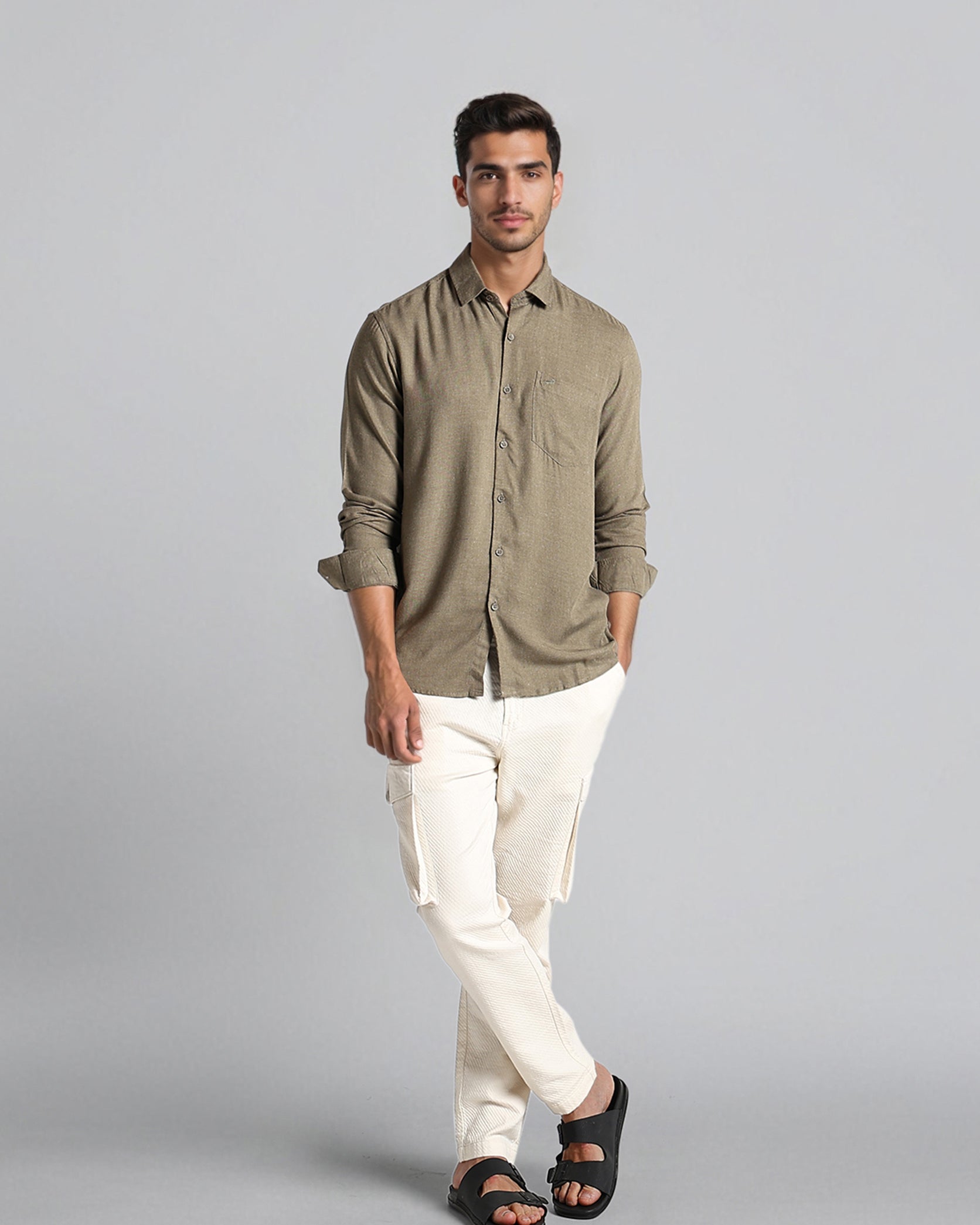 Man wearing a green shirt and white pants on a gray background