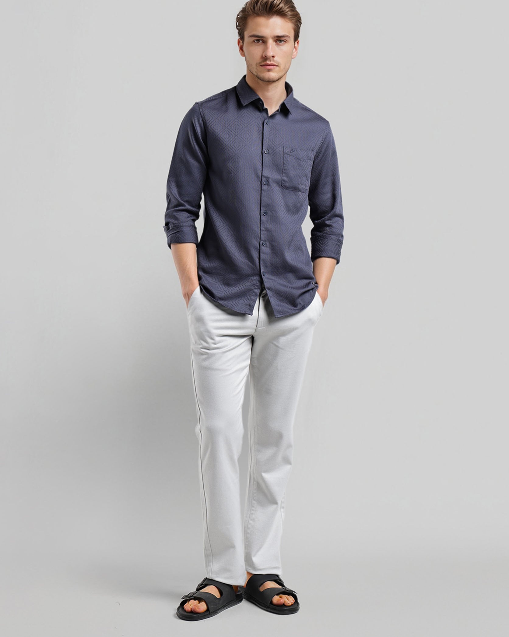 Man wearing a blue shirt and white pants on a gray background