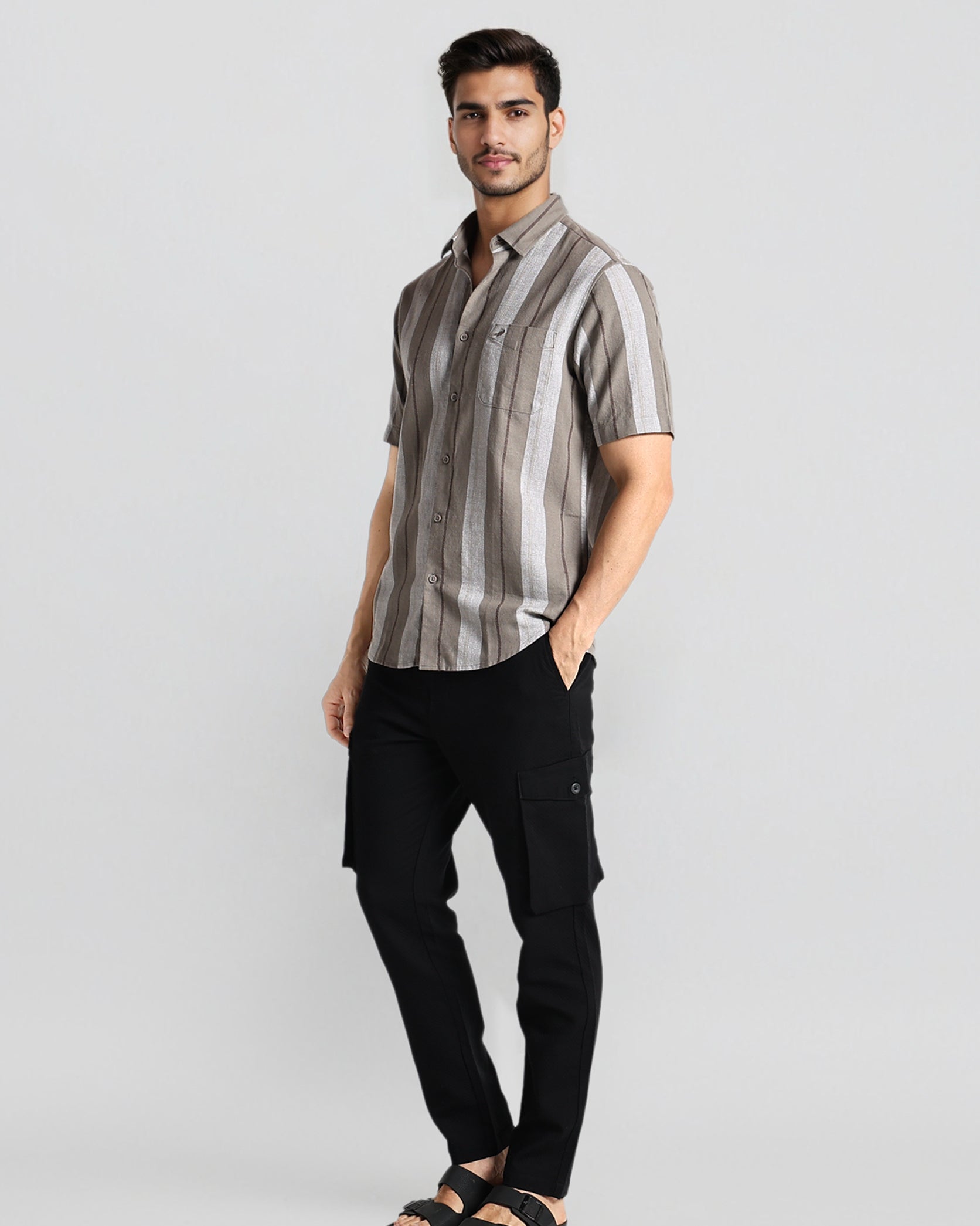 Man wearing a striped shirt and black pants on a light gray background