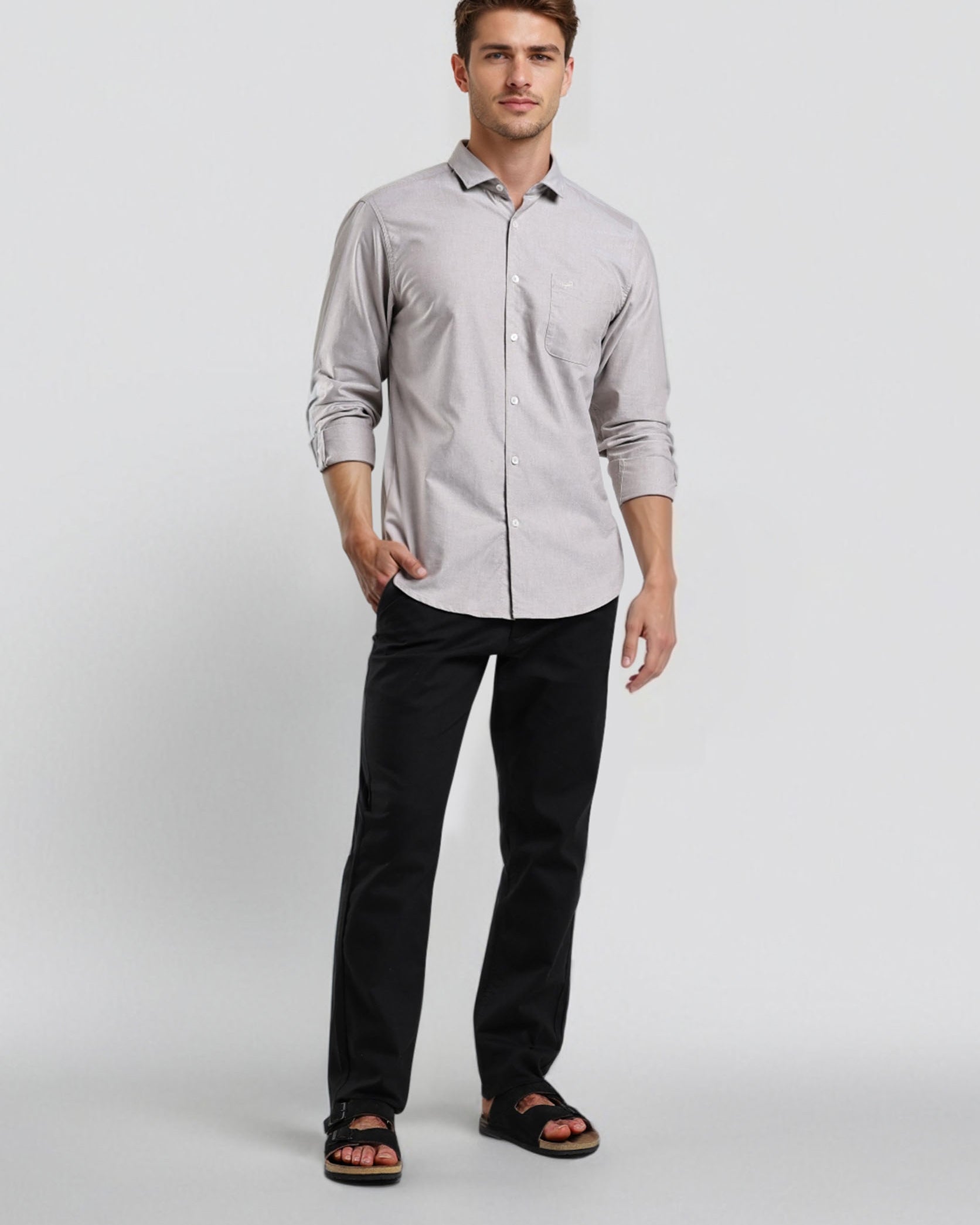 Man wearing a light gray button-up shirt and black pants on a white background