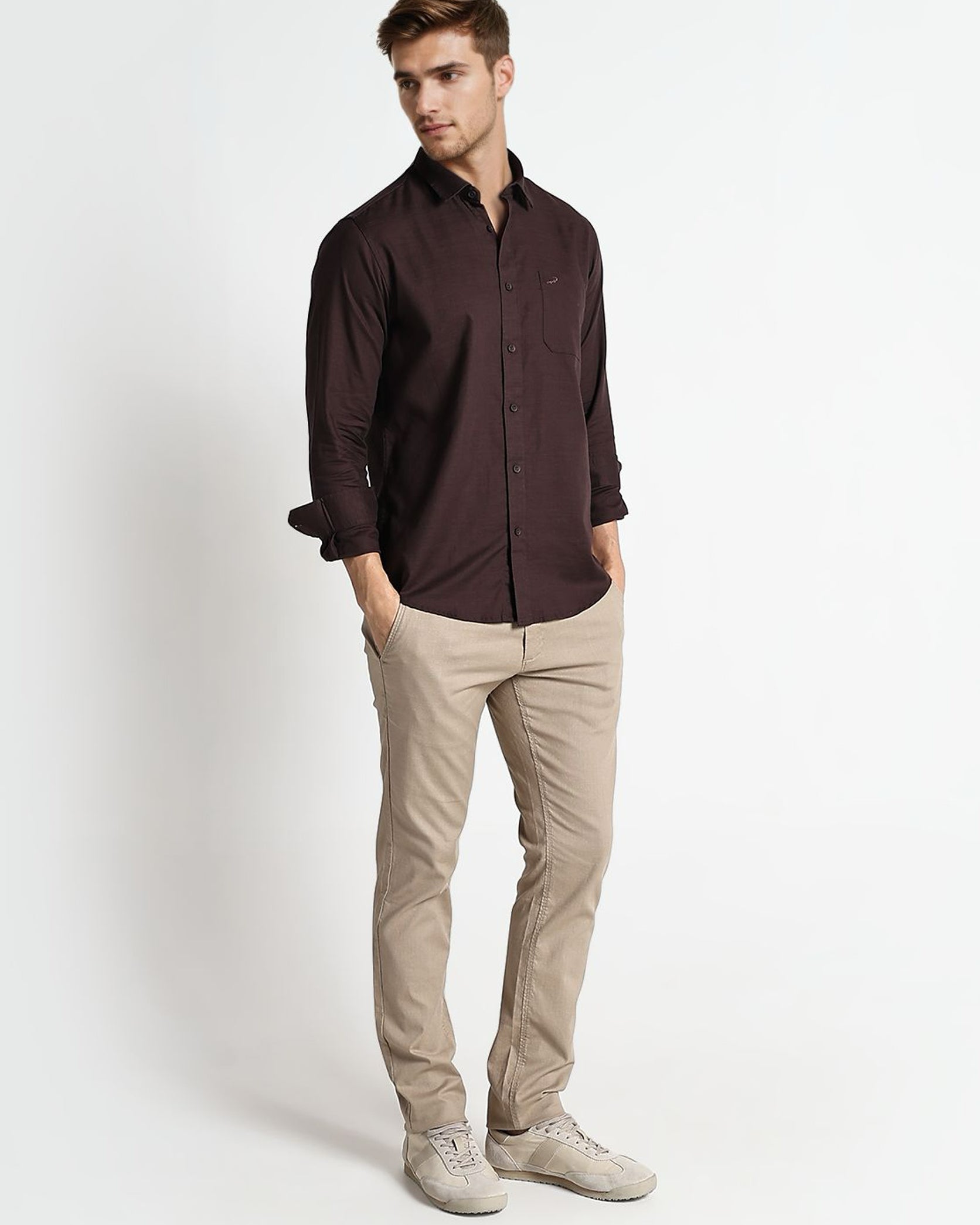 Man wearing a dark brown shirt and beige pants on a white background