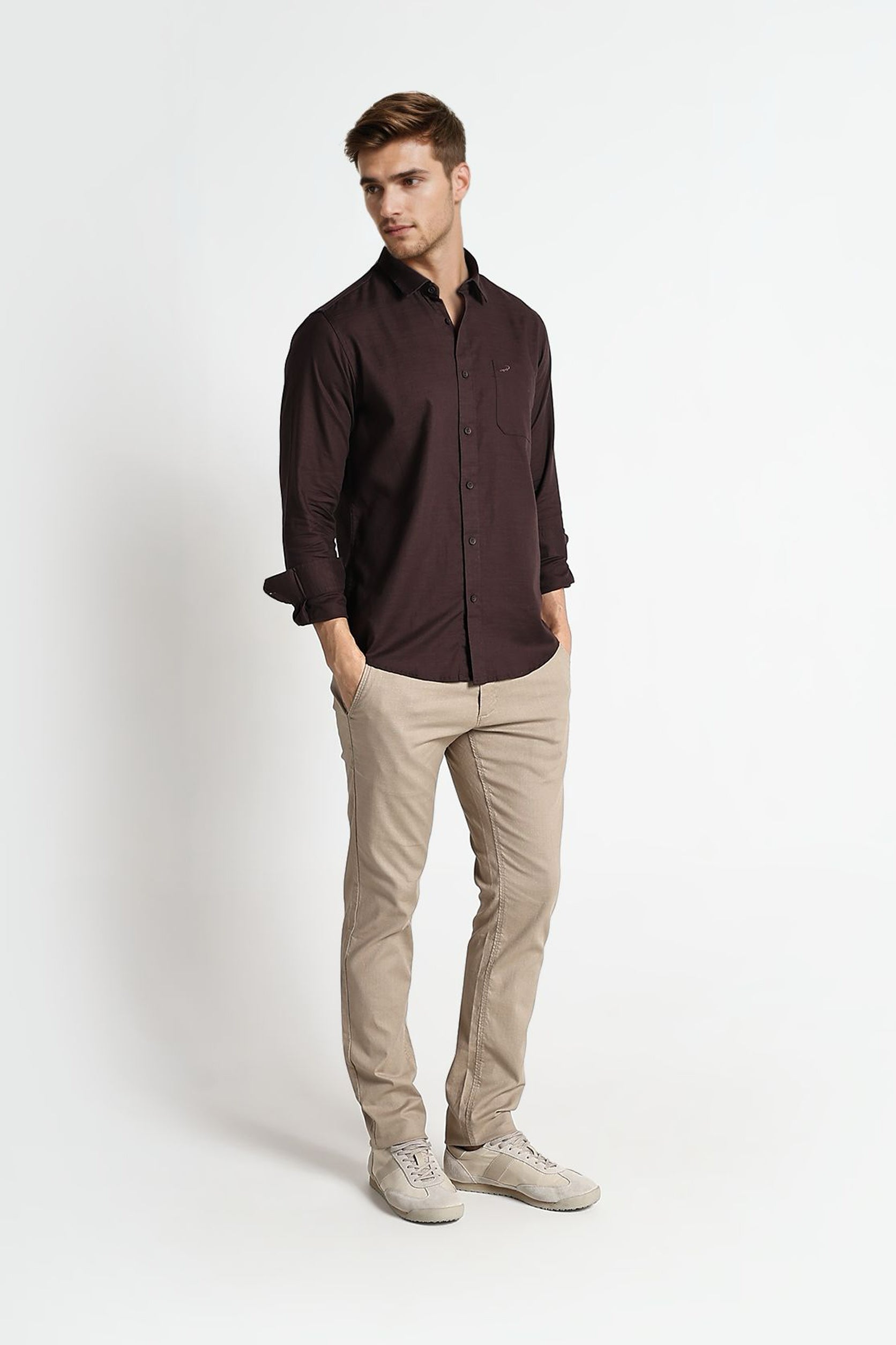 Man wearing a dark brown shirt and beige pants on a white background