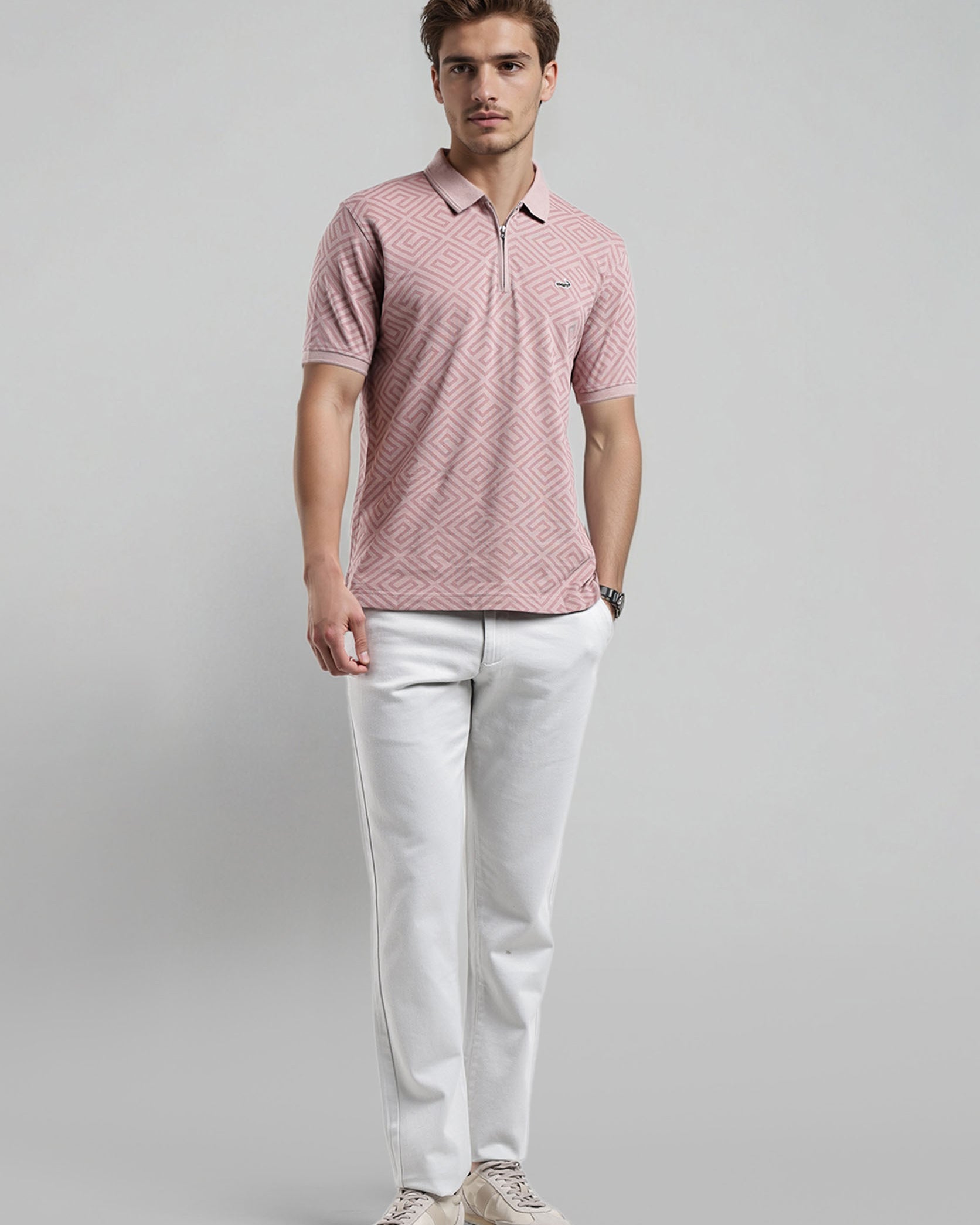 Man wearing a pink patterned polo shirt and white pants on a gray background