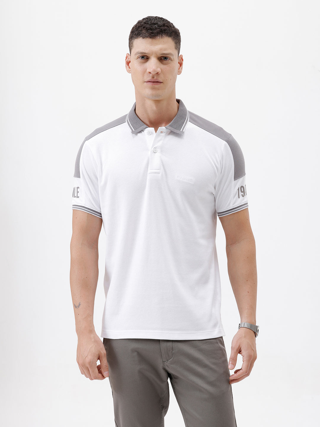 A man modeling a white short-sleeve polo shirt with gray shoulder panels and gray striped trim on the sleeves, paired with gray trousers and black sunglasses, against a plain white background.