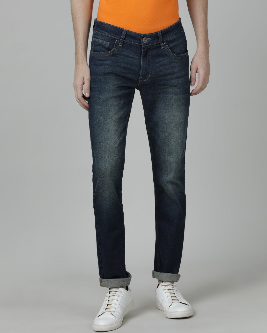 Man wearing a blue medium blue solid mid rise slim fit jean on a light gray background