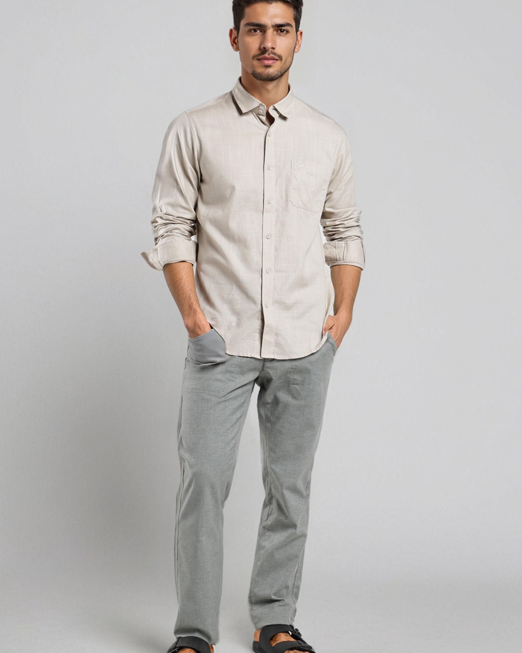 Man wearing a beige shirt and gray pants on a white background